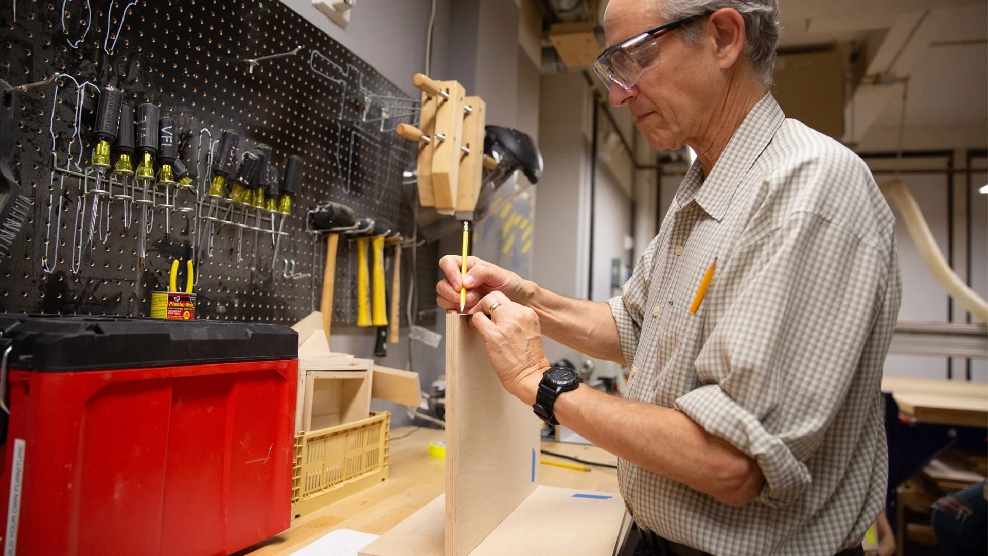 Man drawing on a piece of wood in a woodshop