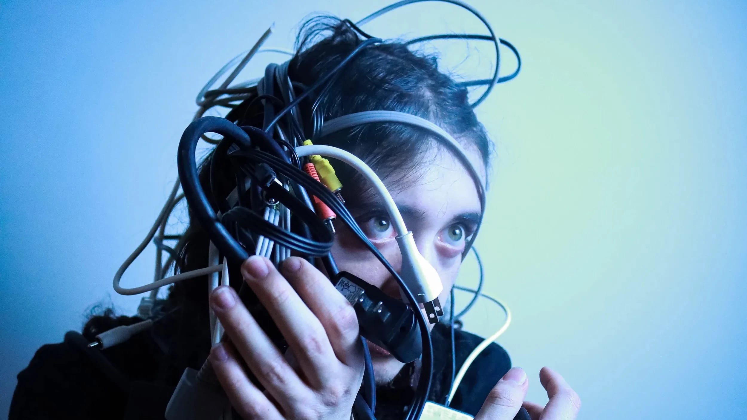 Self-portrait, a head covered in wires/cables, with cold, blue lighting.
