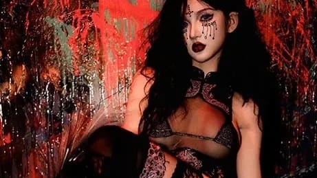 A woman in black lingerie sits with her legs crossed.