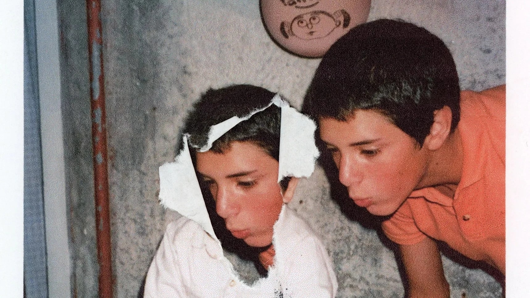 Color photograph of a child blowing out a birthday cake for a younger child.