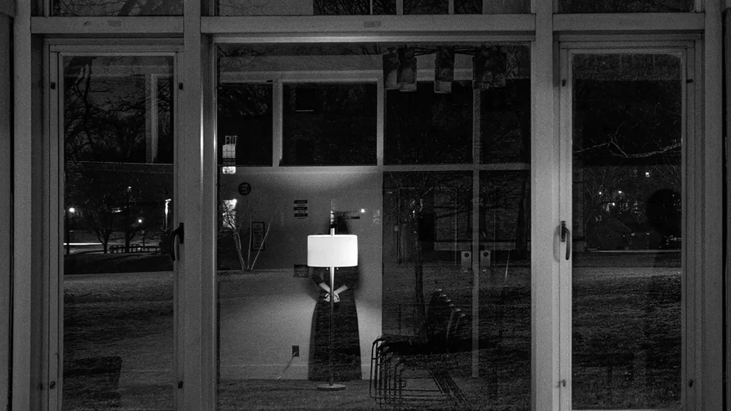 A black and white photo displays reflections in a window and the scenery outside.