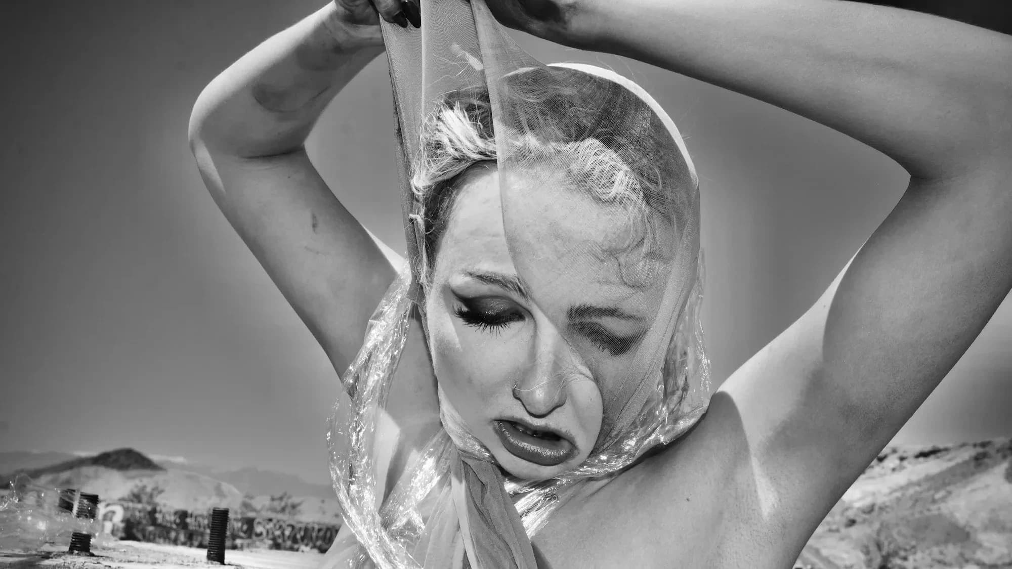 Black and White inkjet photograph of a woman in despair, tearing off pantyhose and cellophane wrap. Takes place in Las Vegas desert.