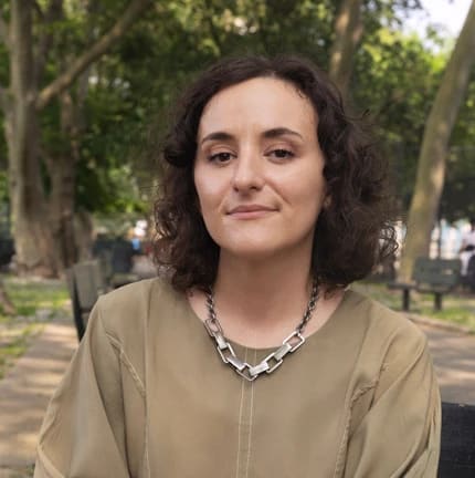 Portrait of Lily Padula, she is sitting in a park wearing a green dress