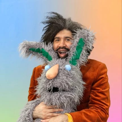Portrait of Jayson Musson smiling and holding a large stuffed rabbit