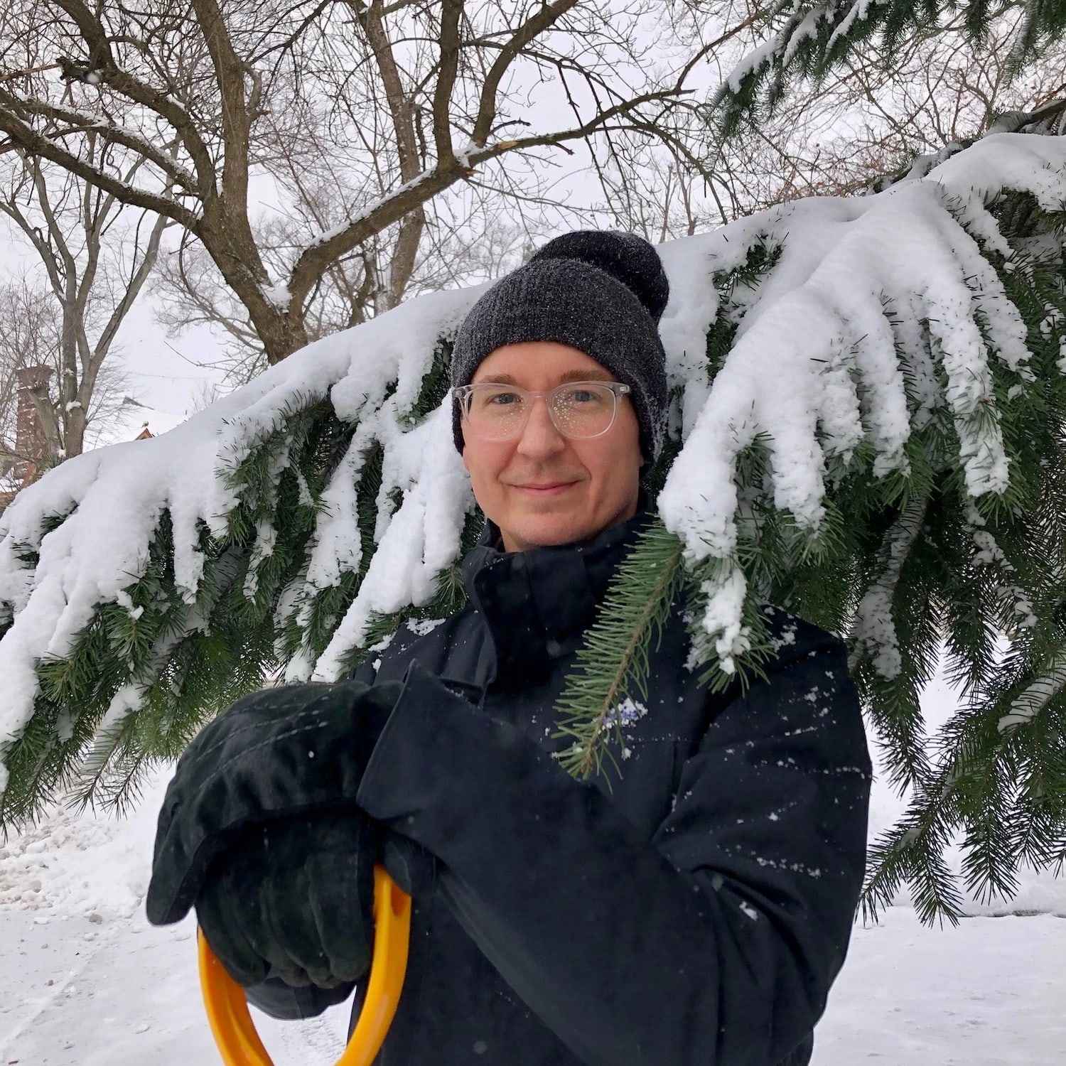 man standing in snow by a tree