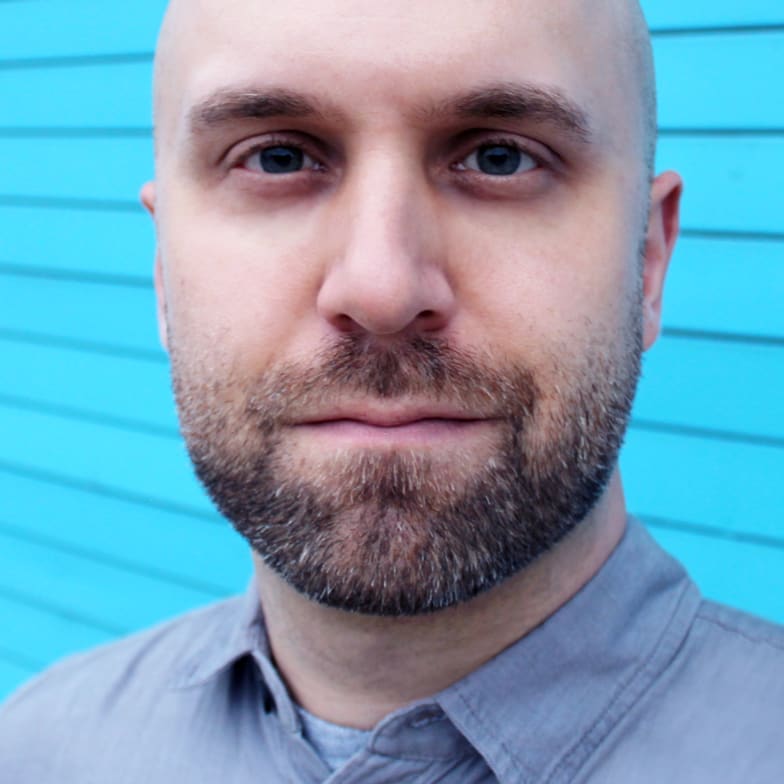 Portrait of Tim Szetela against a blue painted wall