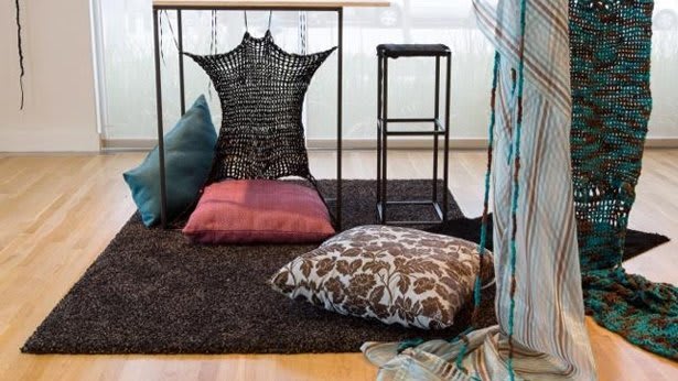 A piece of carpeting and miscellaneous pillows sitting in a room with a wood floor.