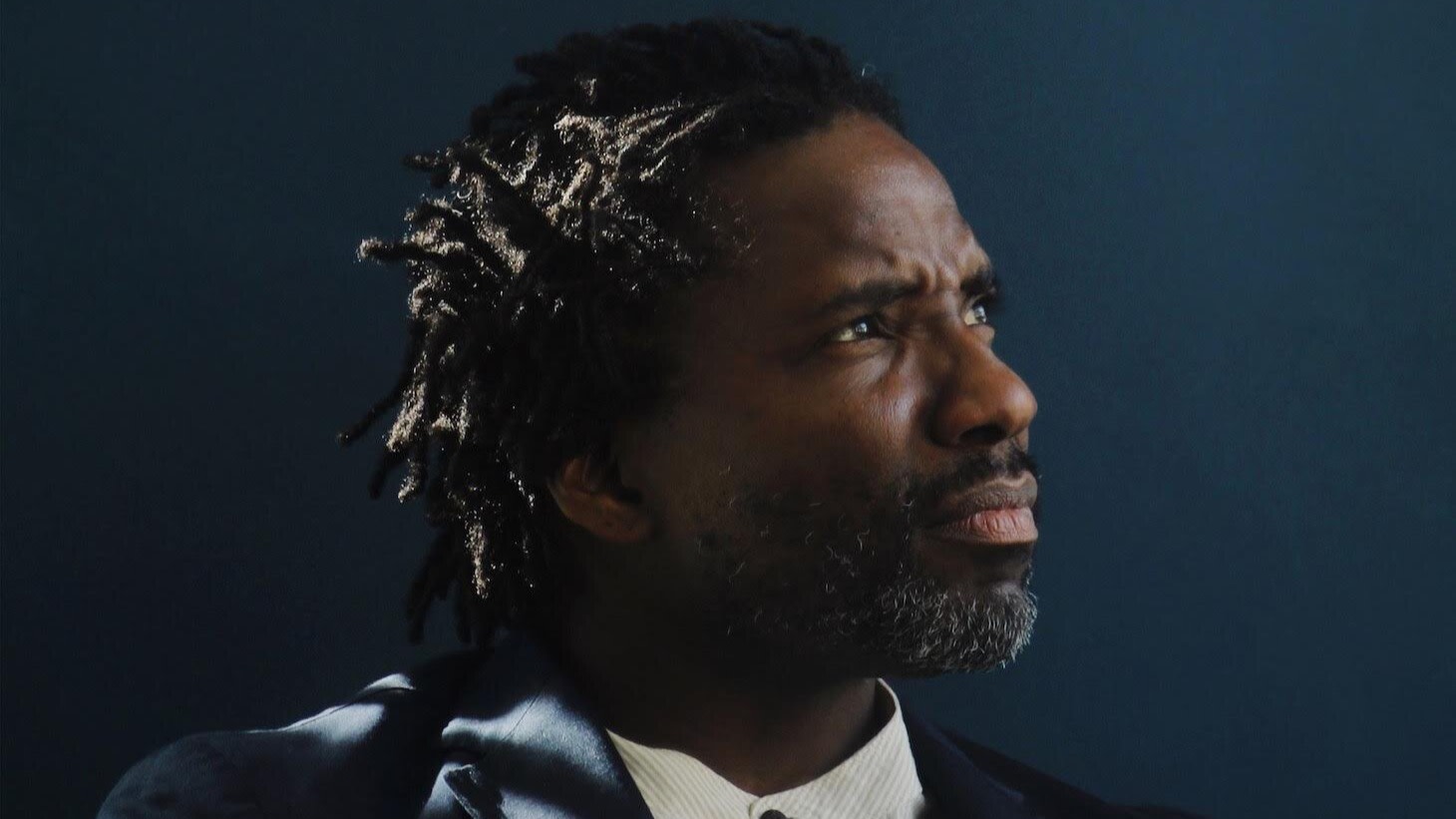 Portrait of Seph Rodney in suit in front of dark background