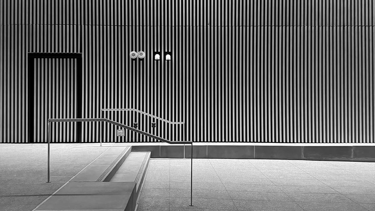 Interior Black and White of a Corporate Building Entrance, with captivating stripes for verticality texture and streamlined steps in front. 