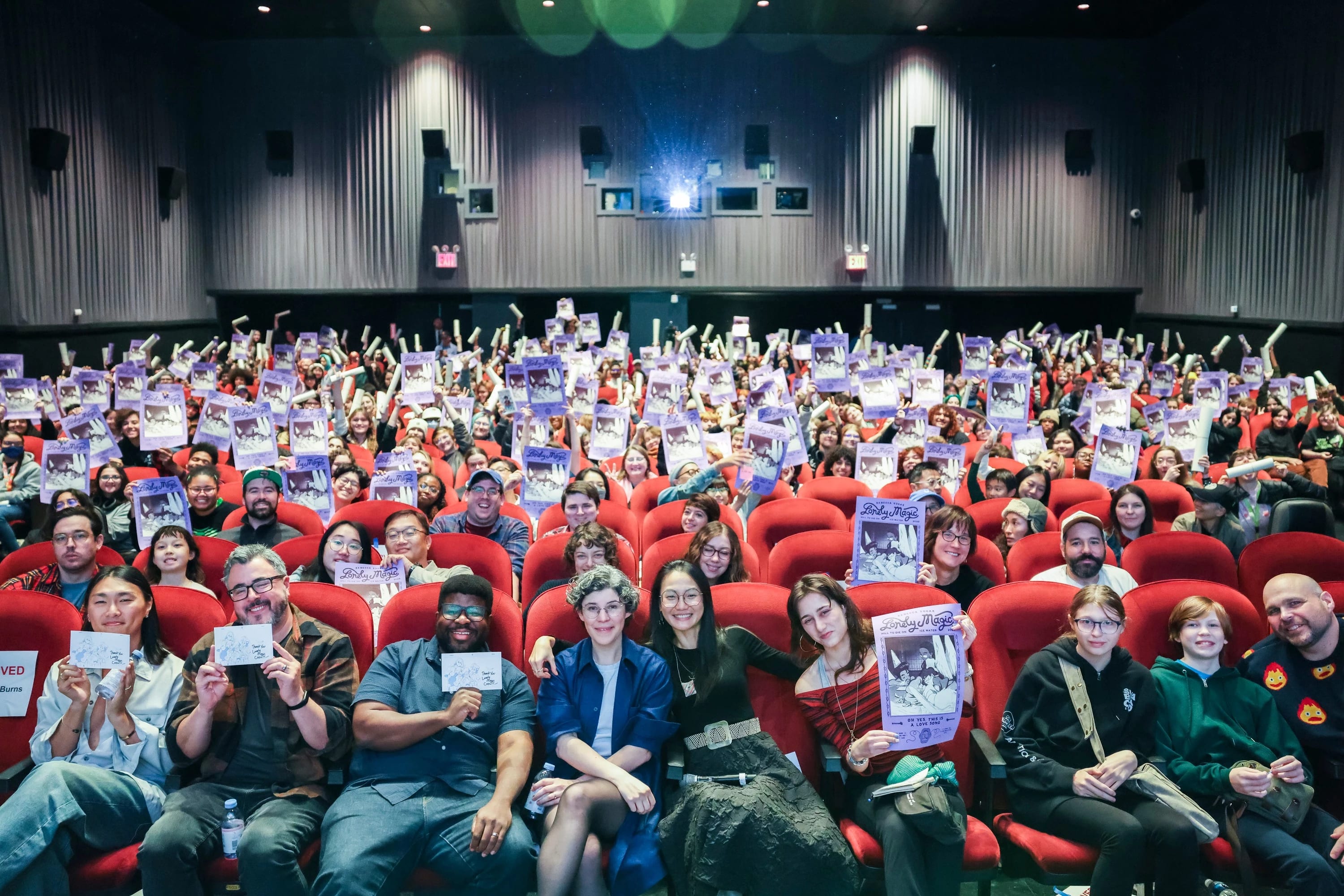 ALT-text: A large seated group holding posters for a group photo.
