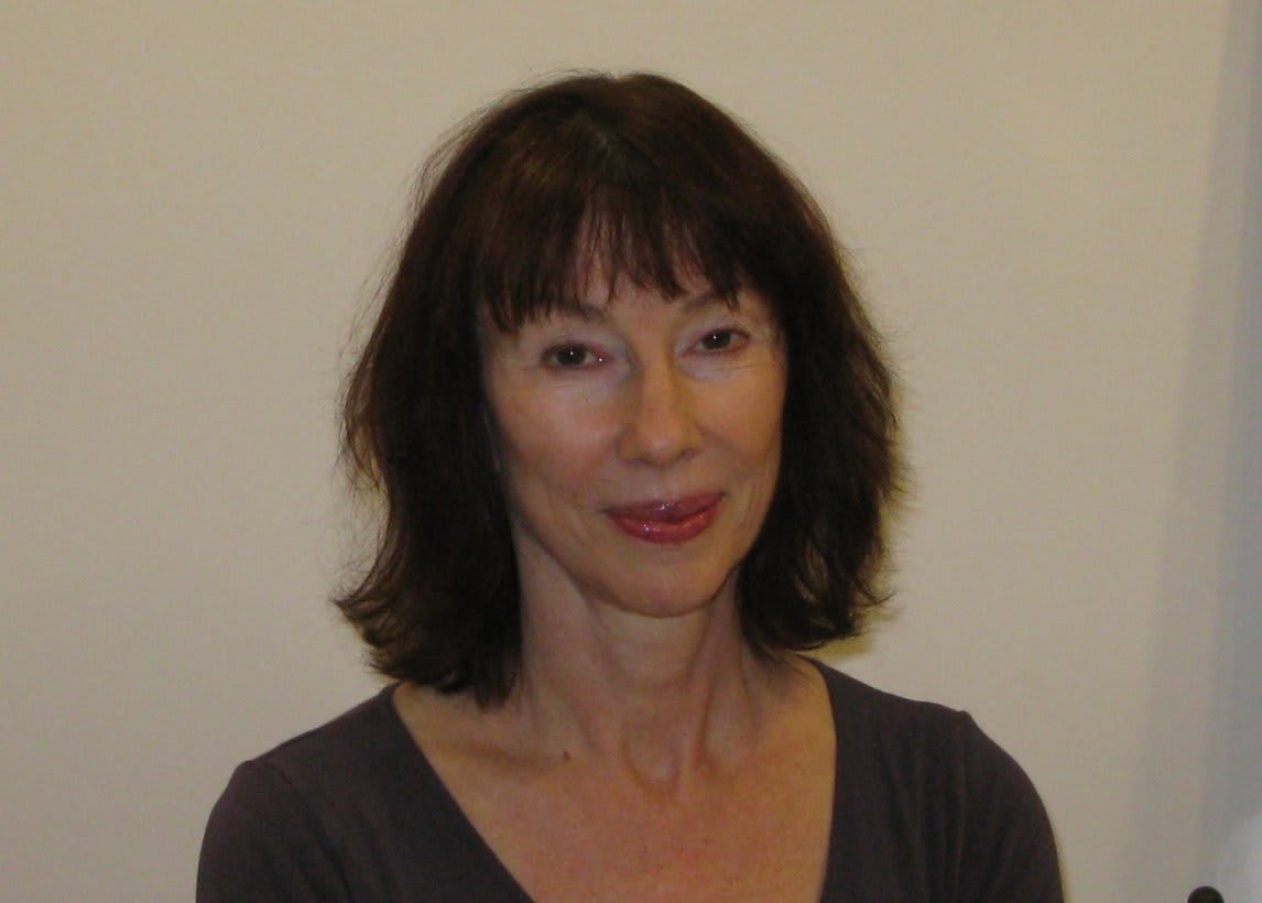 A kind, smiling woman in a gray shirt.