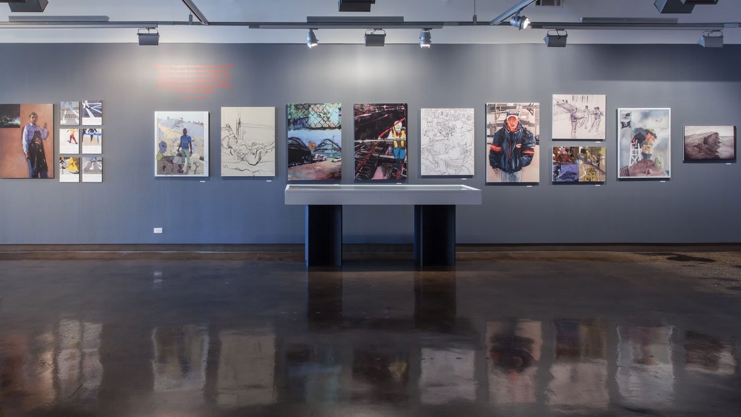 A display table before a wall covered in paintings of people.