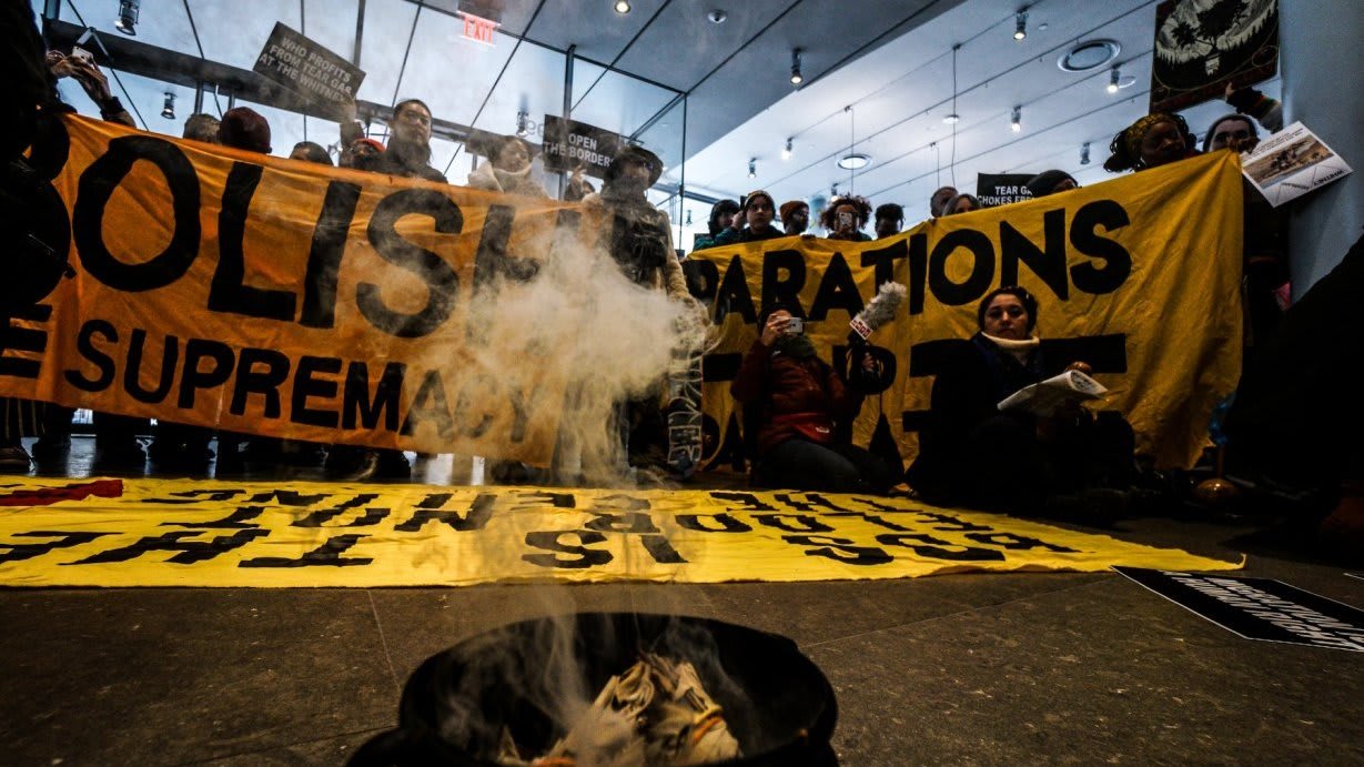 An image of a group of people protesting around a smoking pot.