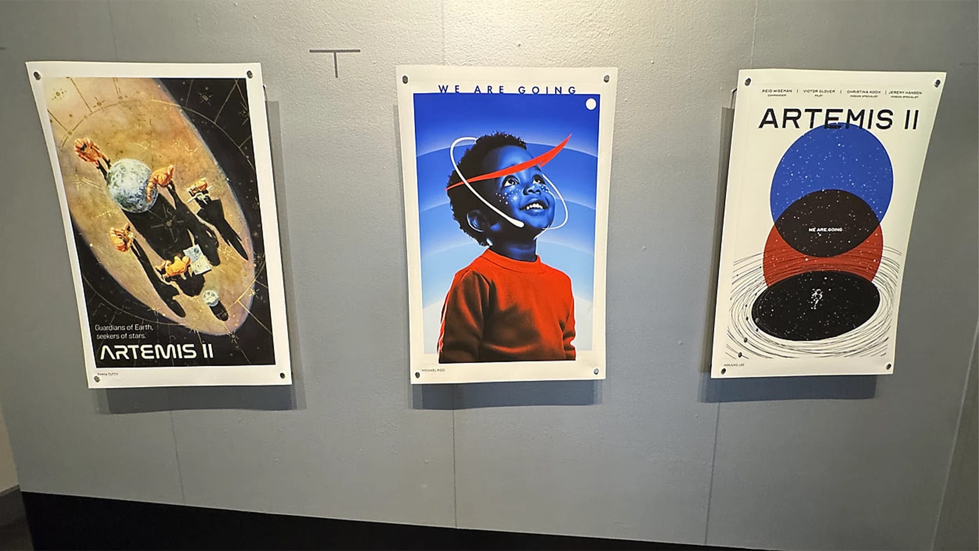 Three ARTEMIS II posters designed by SVA students on a gray wall.