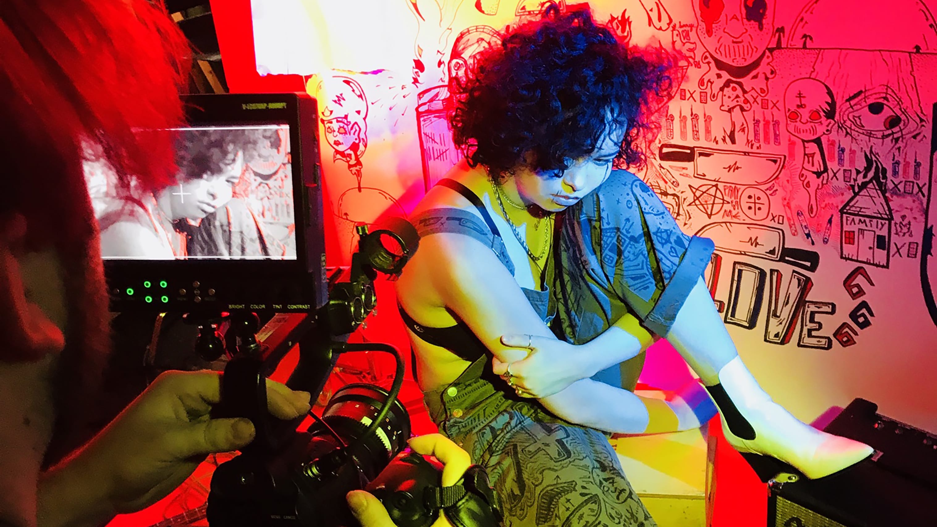 woman sitting in front of camera with bright colored lighting.