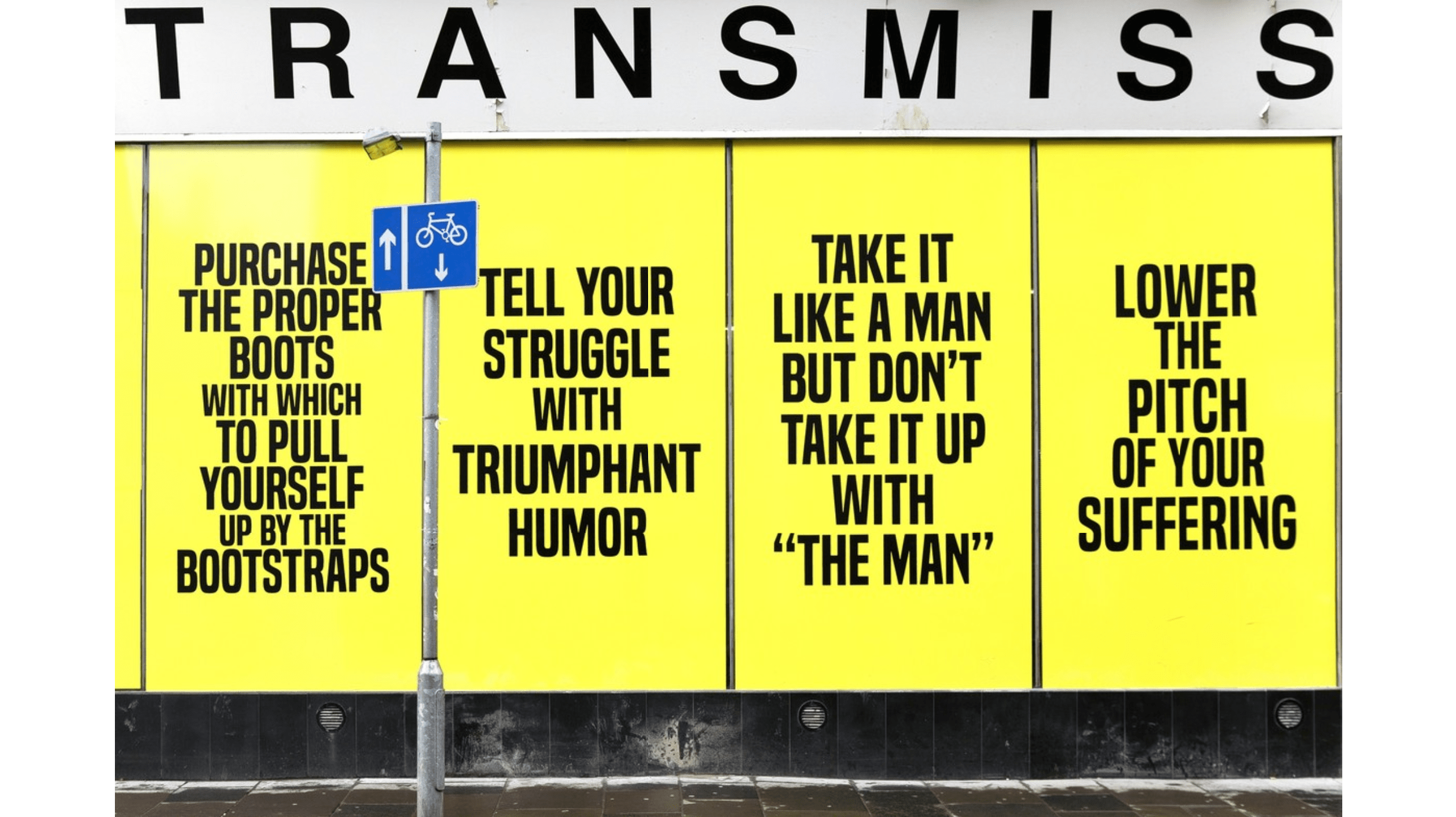 A photograph of a number of text-based posters, with black type against a yellow background, that have been installed side by side on what appears to be a building exterior on a city street.