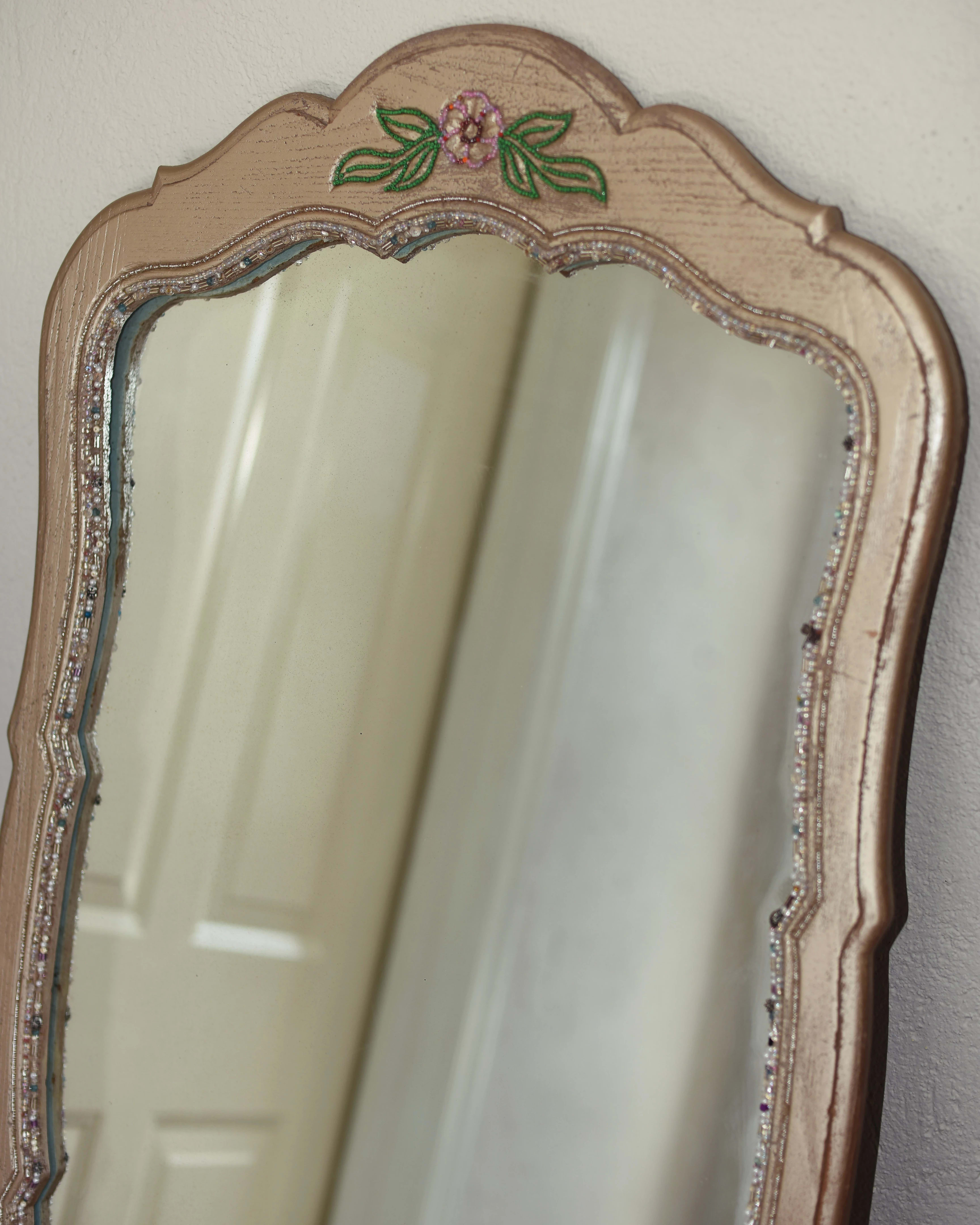 Photograph of a large mirror with a gilded frame, leaning against a wall with a door frame reflected within.