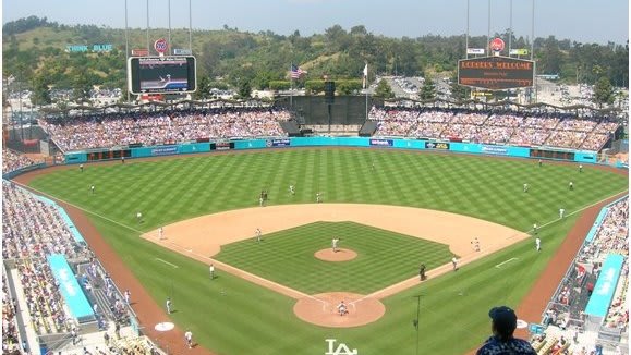 There is a baseball and people watching the game in the stadium. There is a large crowd in the stadium.