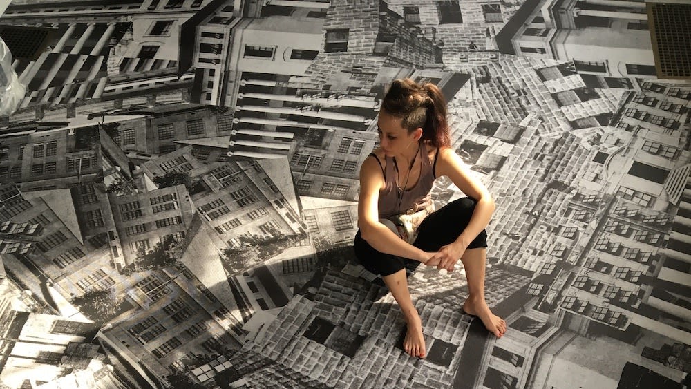 Woman in tank top and leggings sits on top of newsprint