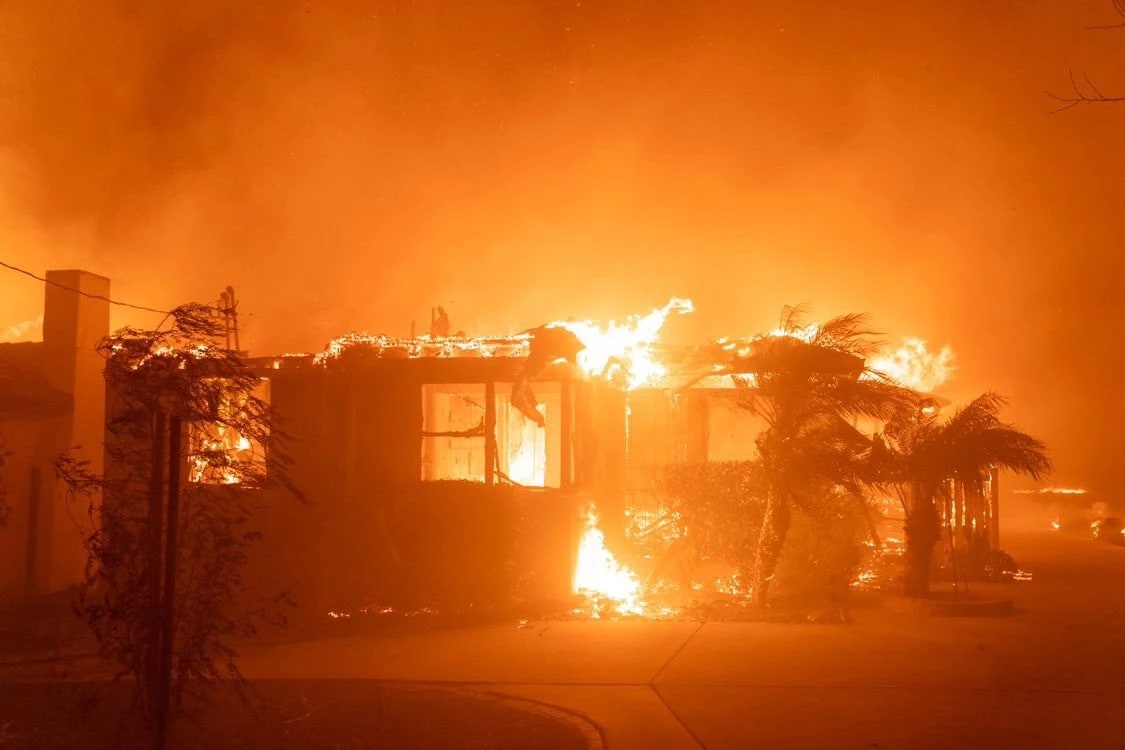 A house ablaze at night, flames consuming the structure, illuminating the dark surroundings with a fiery glow.