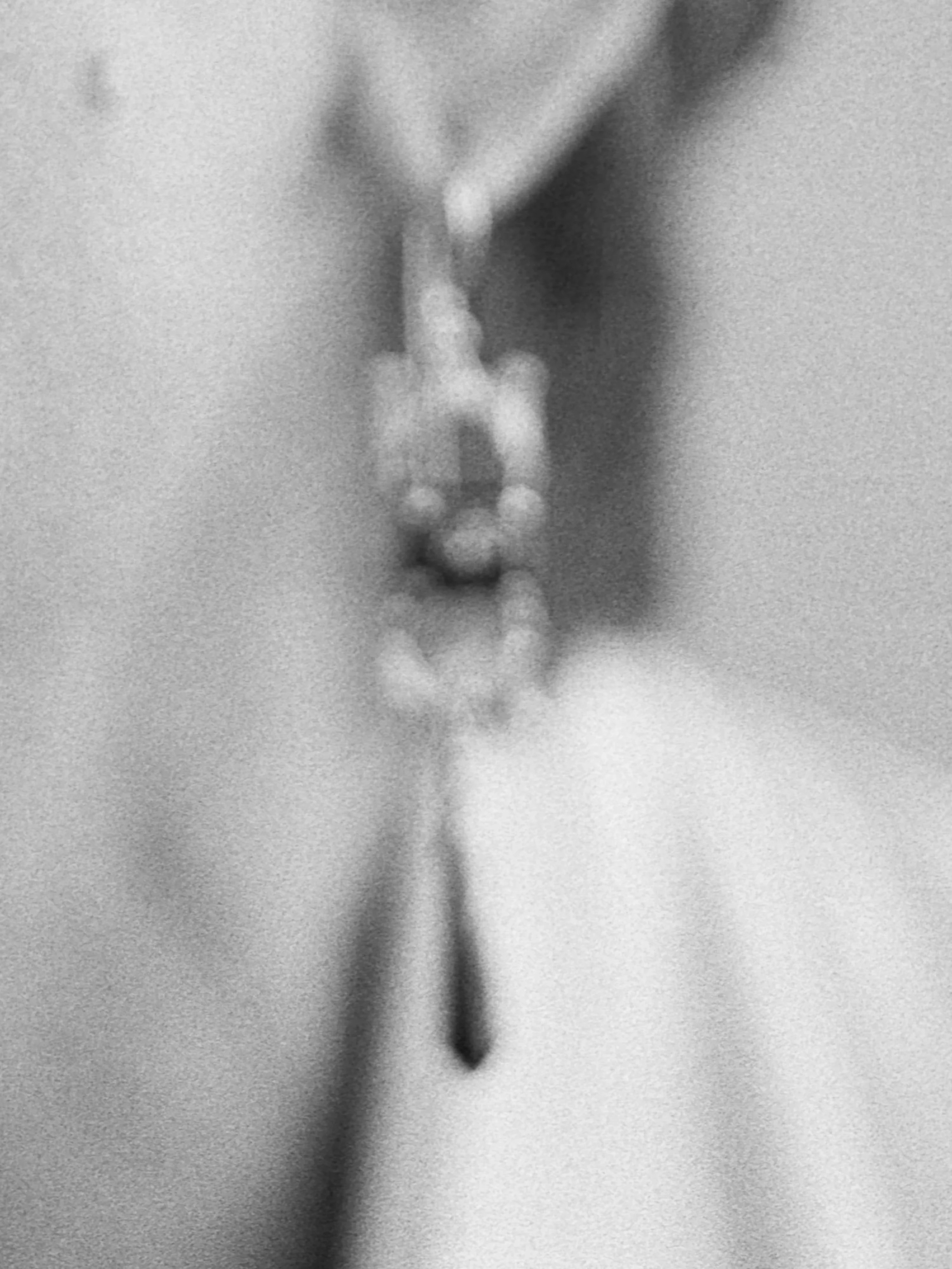 Blurry black and white photograph of a dangling earring.