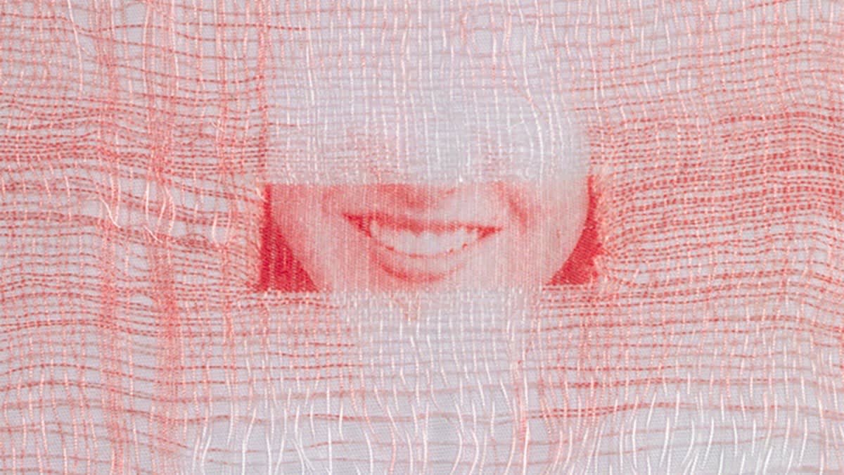 A woven photograph of a closely cropped woman's smile, made of red and white thread.