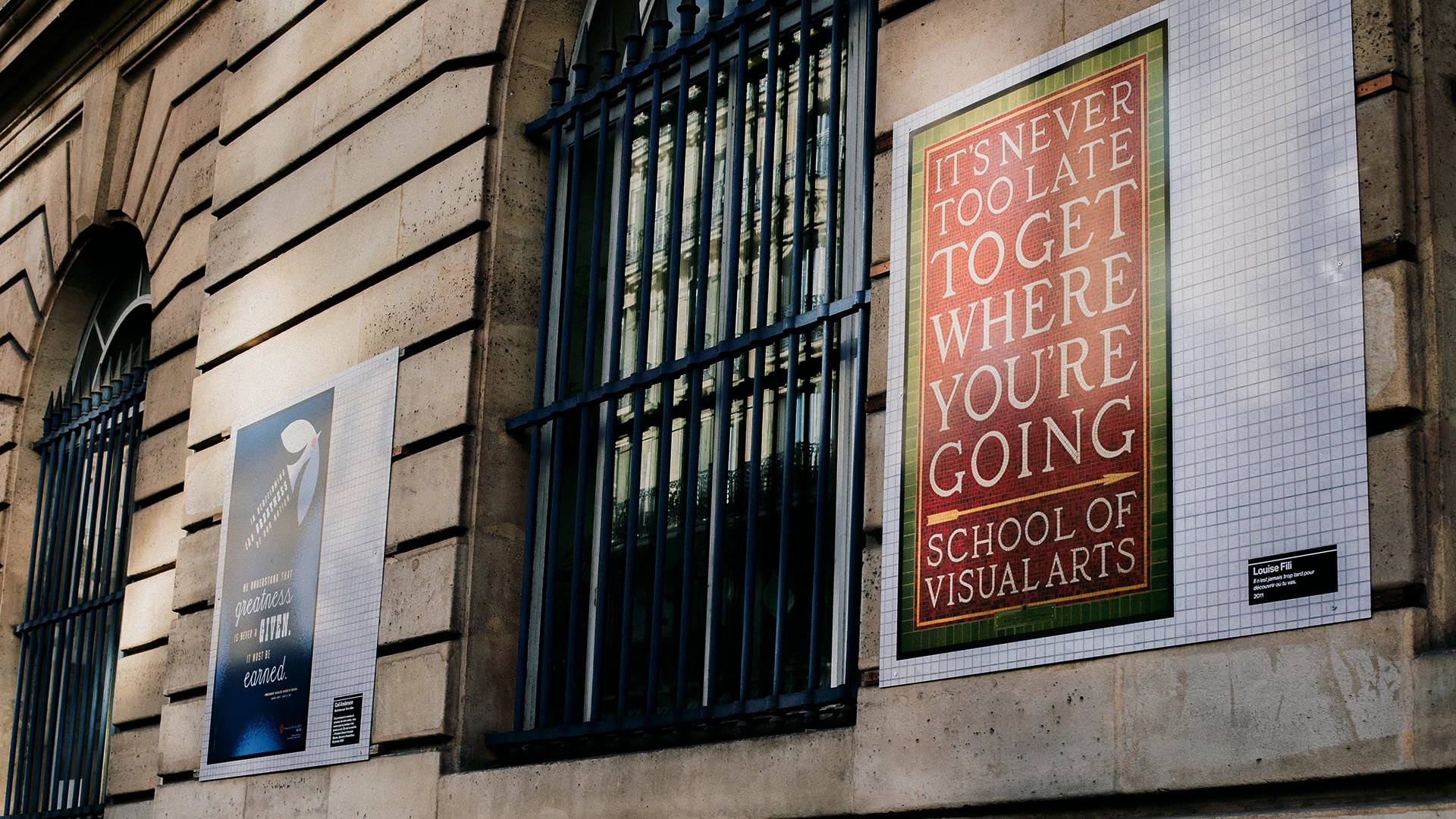 A close up shot of the side of a building, SVA posters up on the side.
