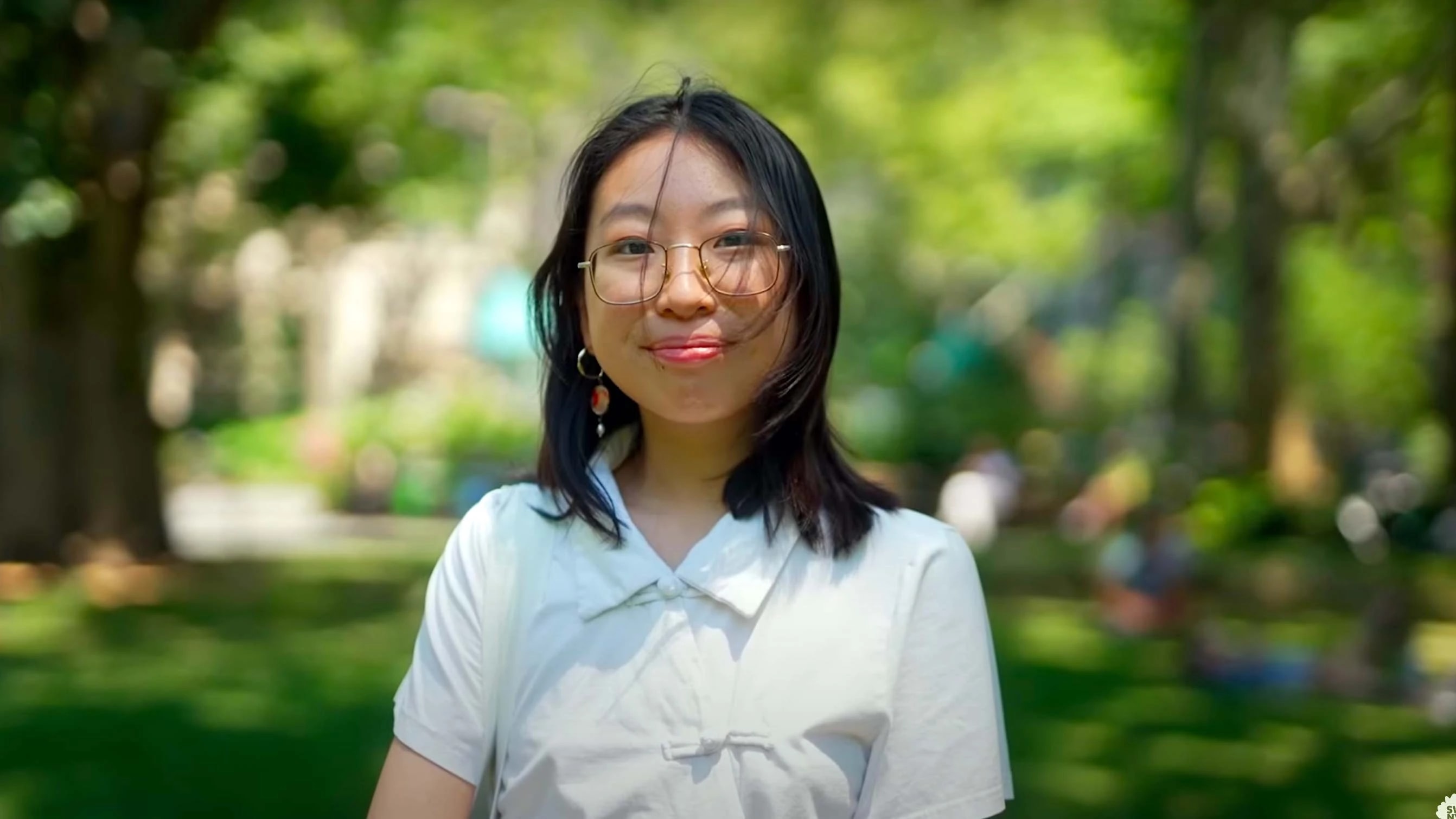 A still image of a young person in a city park on a sunny day.