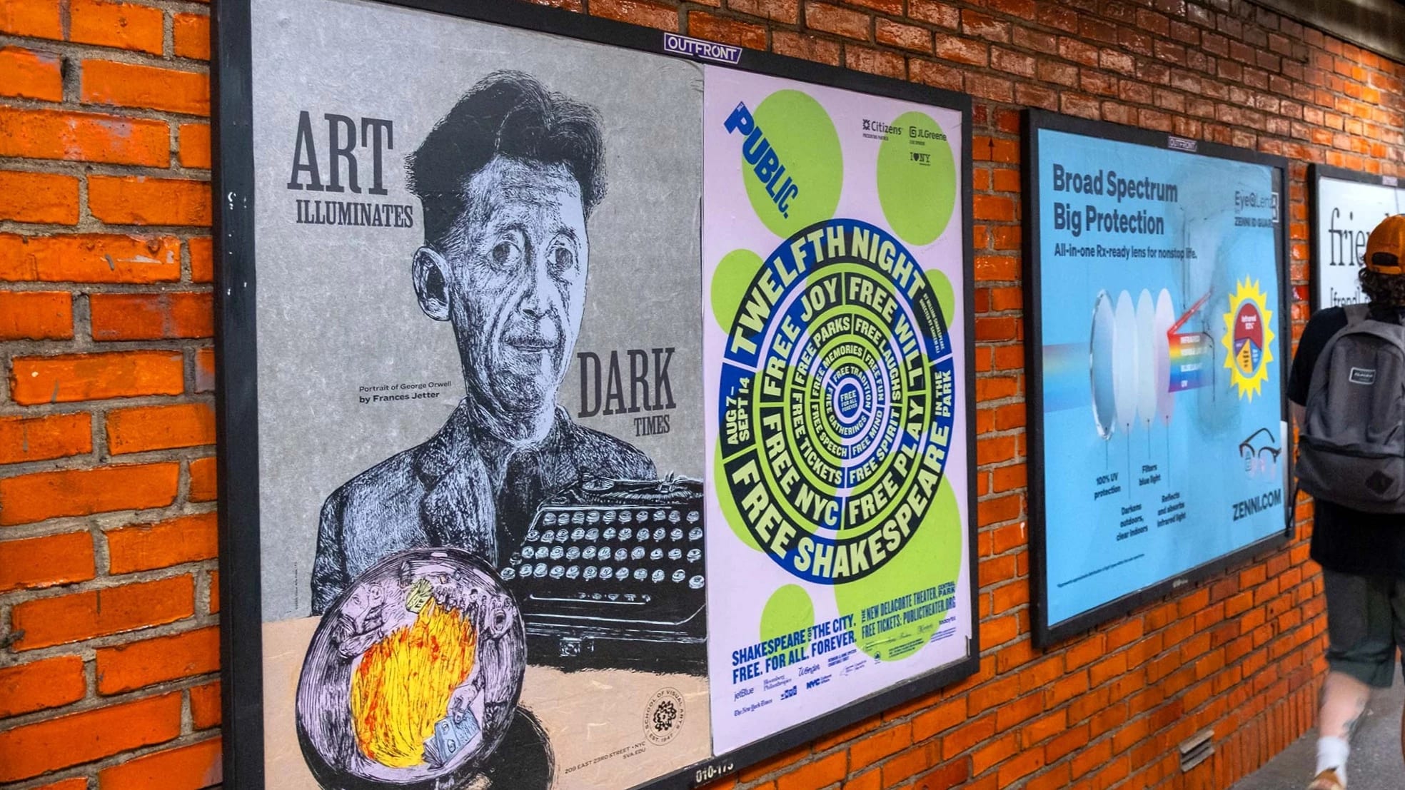 A man strolls past a brick wall adorned with vibrant posters.