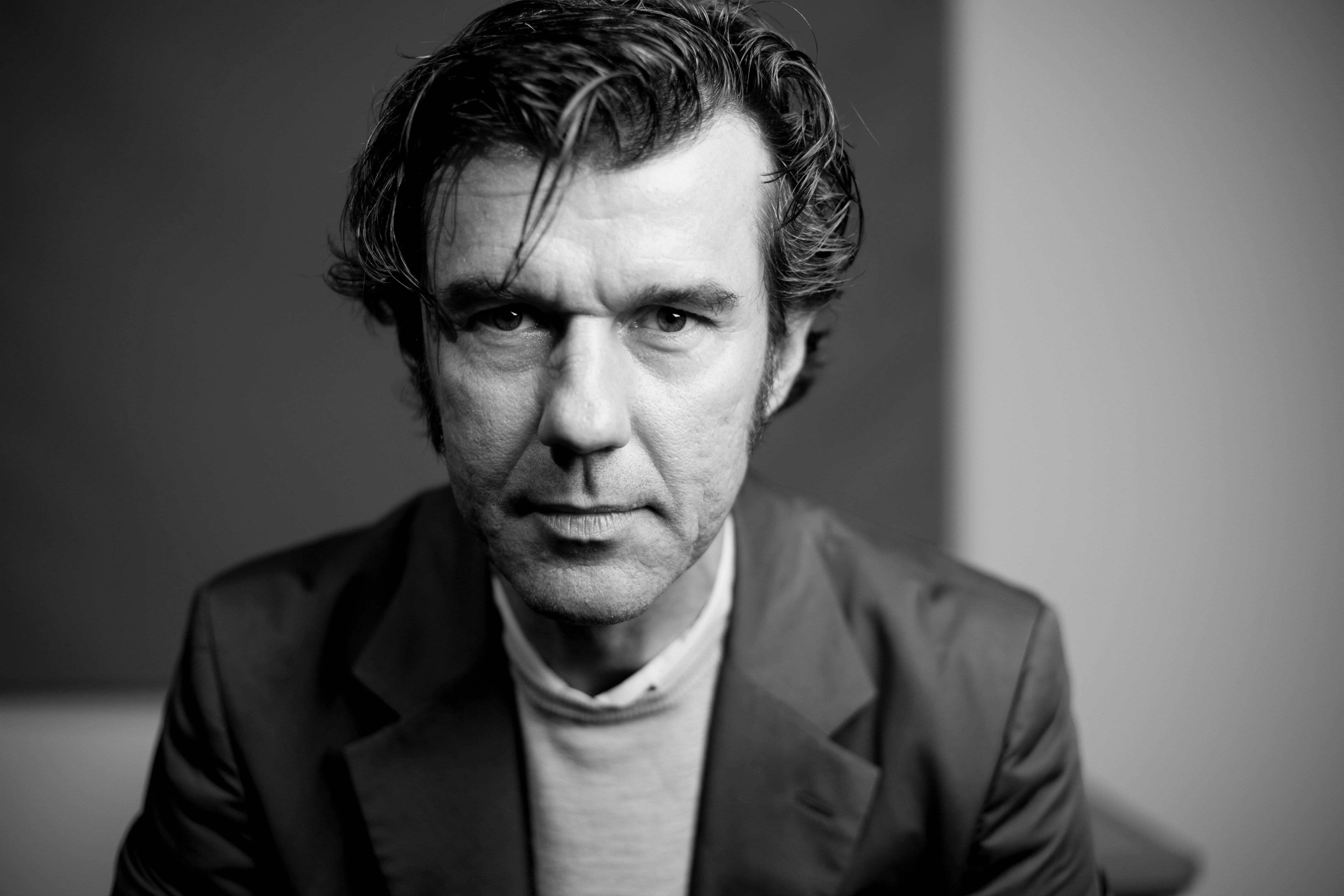 A black and white photo portrait of the designer Stefan Sagmeister.