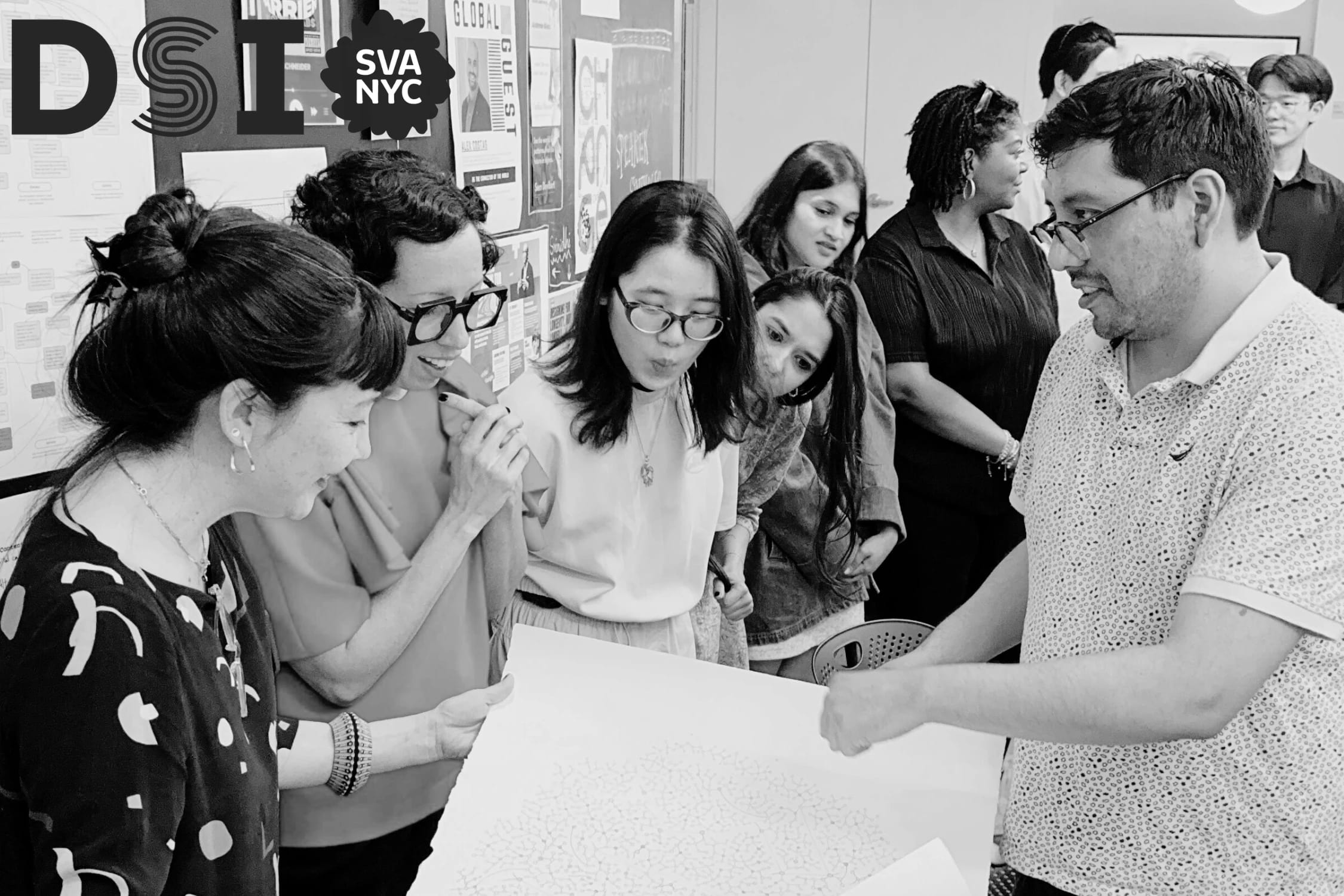 Black and white photo of students with instructors looking at a poster in the middle