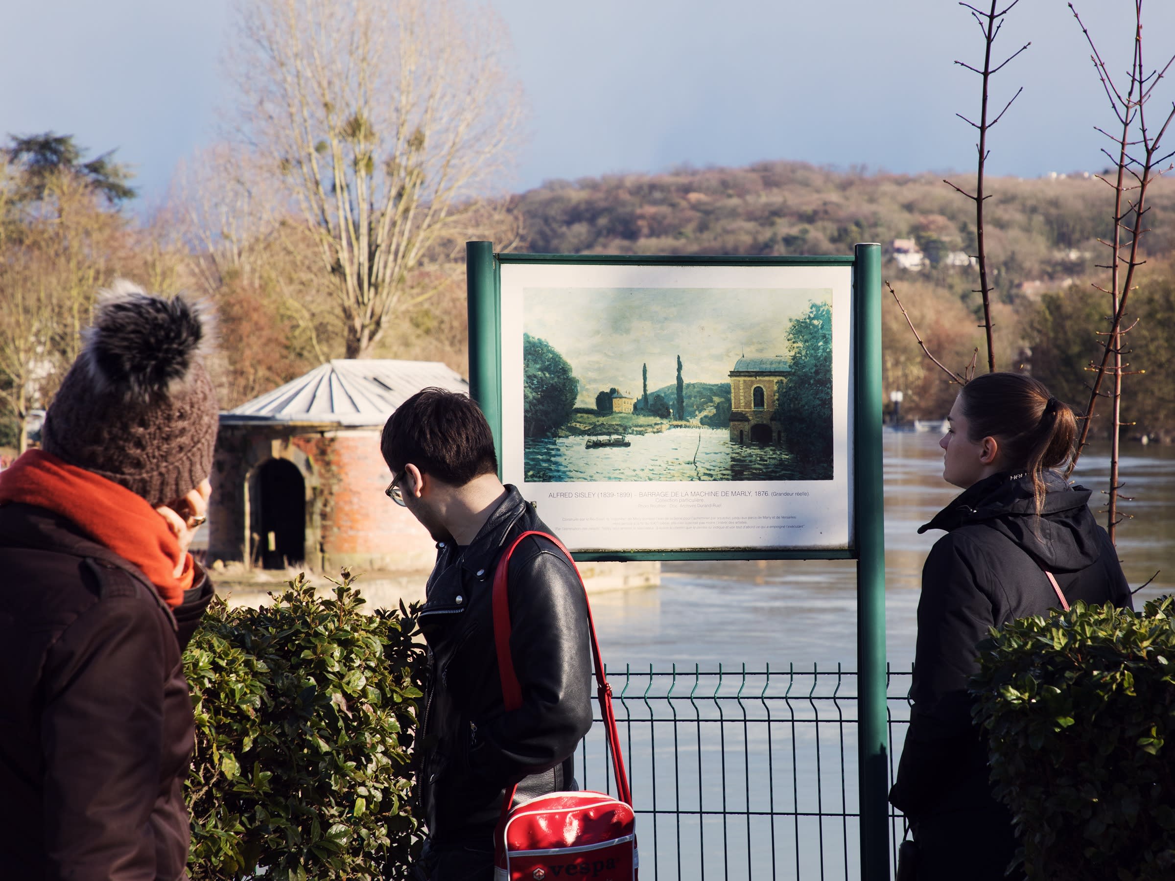 Three people stand in front a French landscape