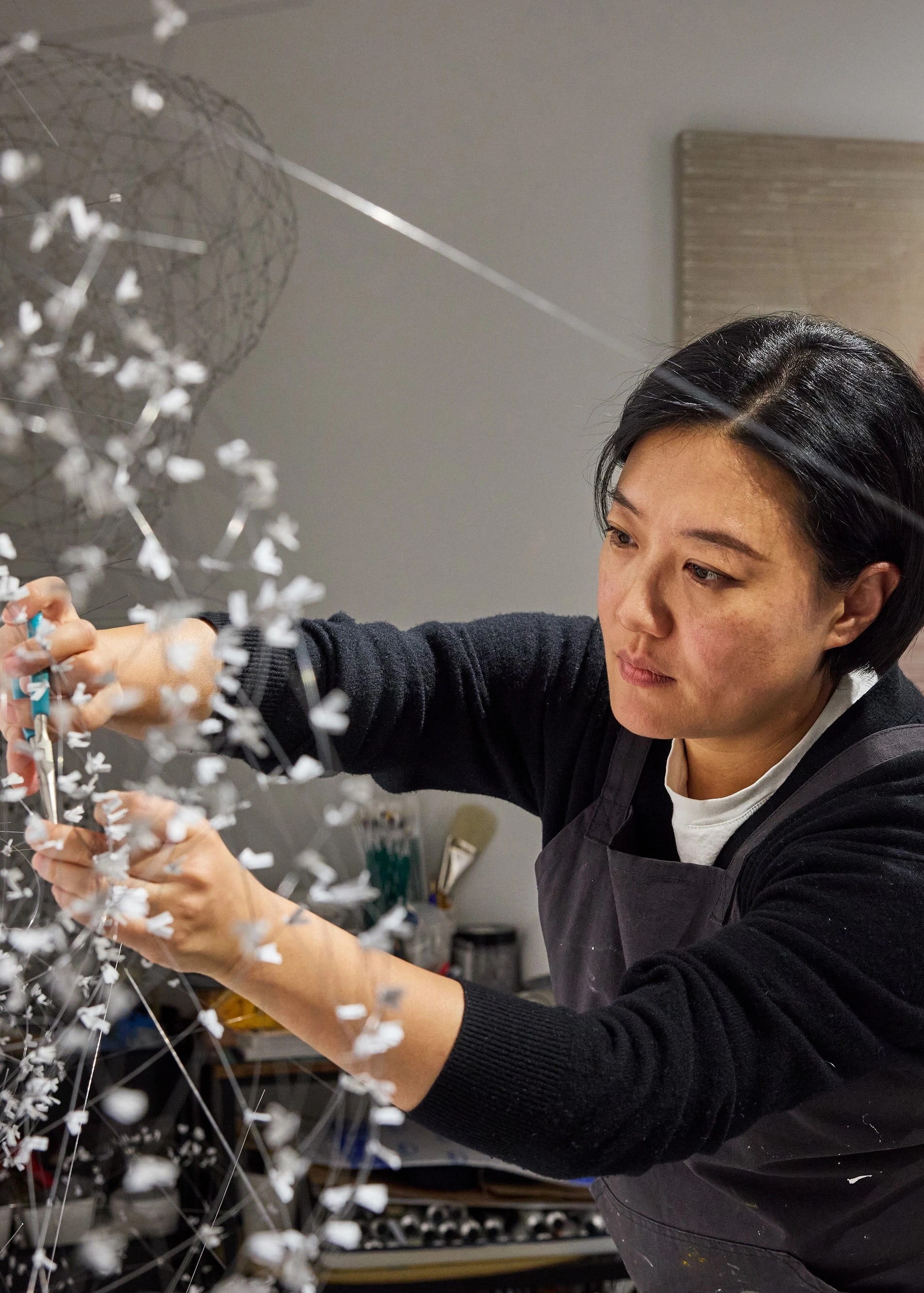 Female artist working intently on a large-scale elaborate wire sculpture in her studio