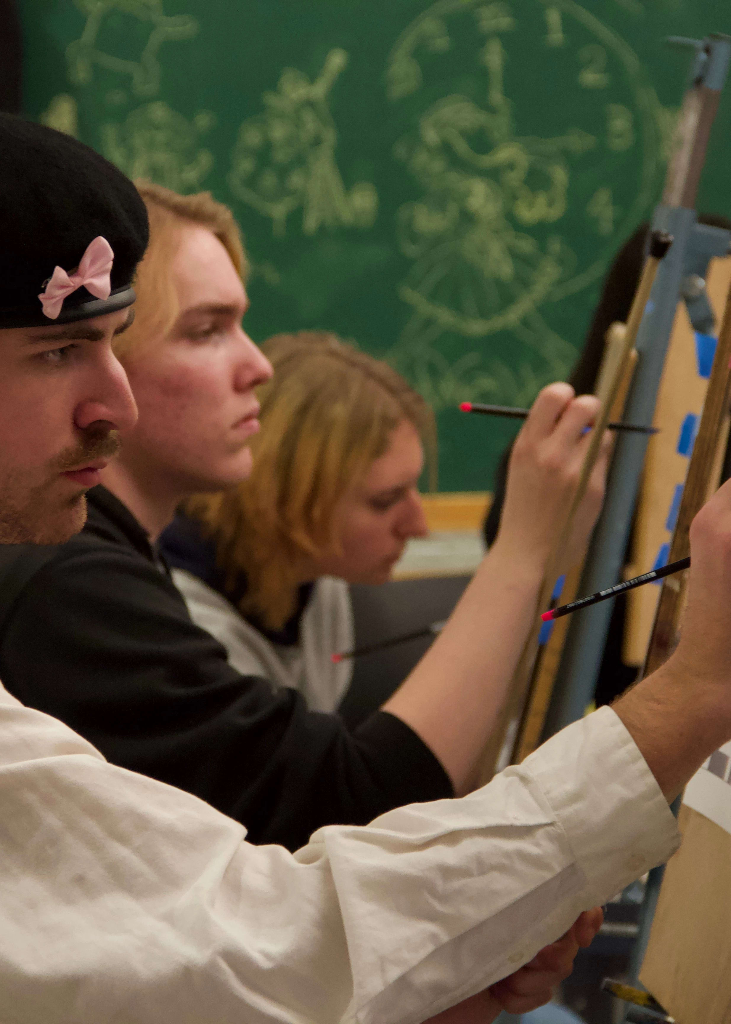 Students working with pencils on easels in a hand lettering class.