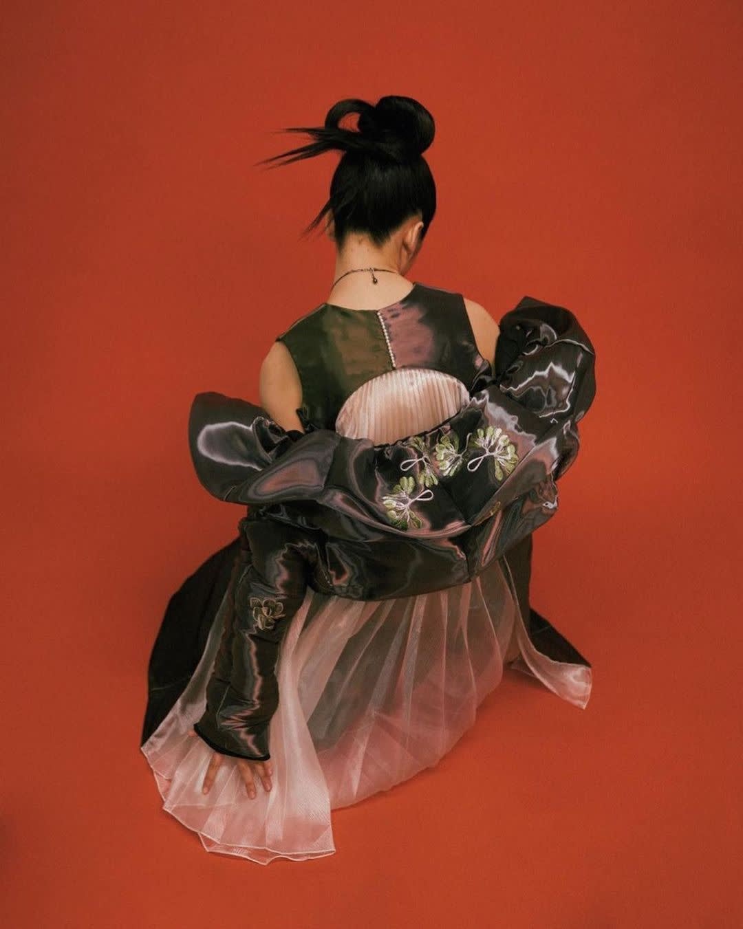 The back of a woman in a dress and jacket on a red background