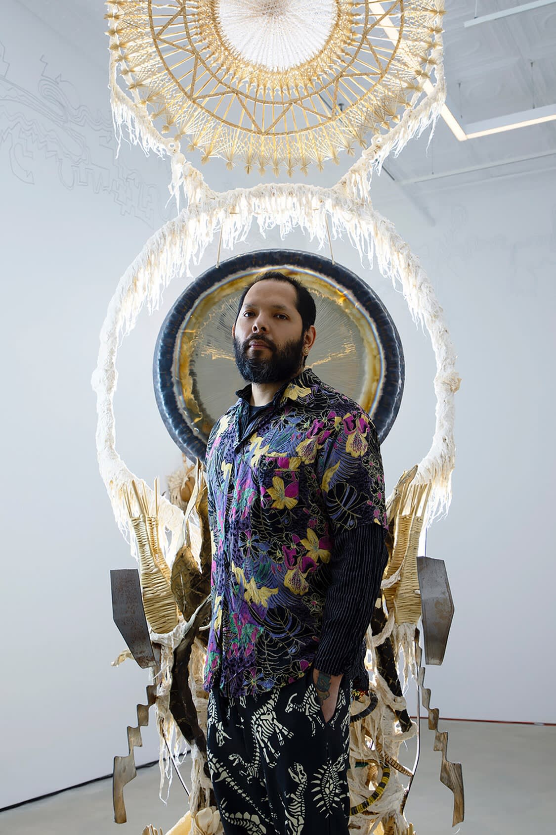 Guadalupe Maravilla poses in front of a large dreamcatcher sort of sculpture