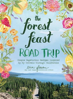 A book cover featuring an image of a lake surrounded by evergreens, all framed by watercolored flowers and fruits. In the center, the title reads, "The Forest Feast: Road Trip".