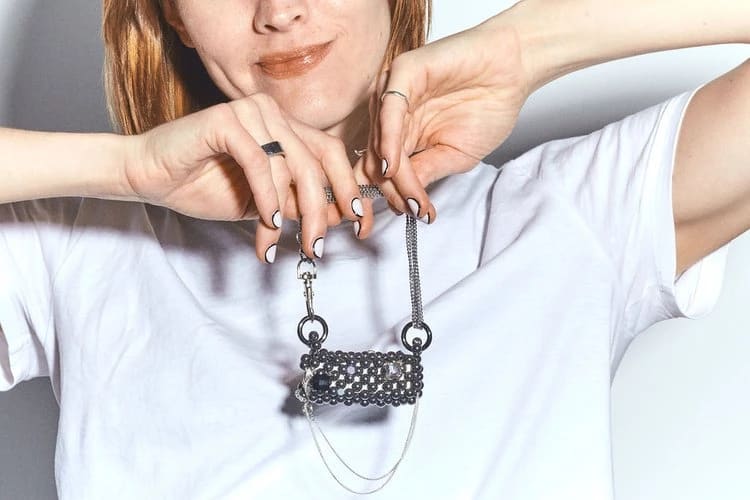 a woman holding a tiny beaded bag