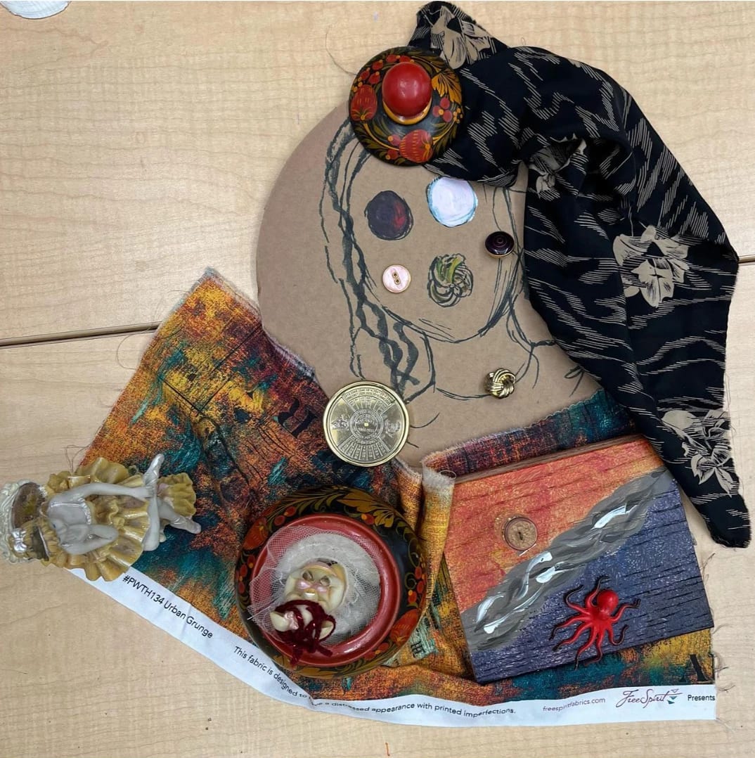 A photo of a collage on a desk, the collage has various fabrics, objects, small toys, and a drawing on cardboard