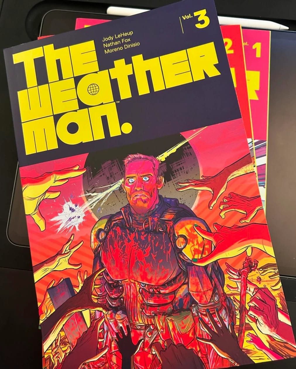 A comic titled "The Weatherman Vol 3" featuring a man in a armour suit being reached for by hands