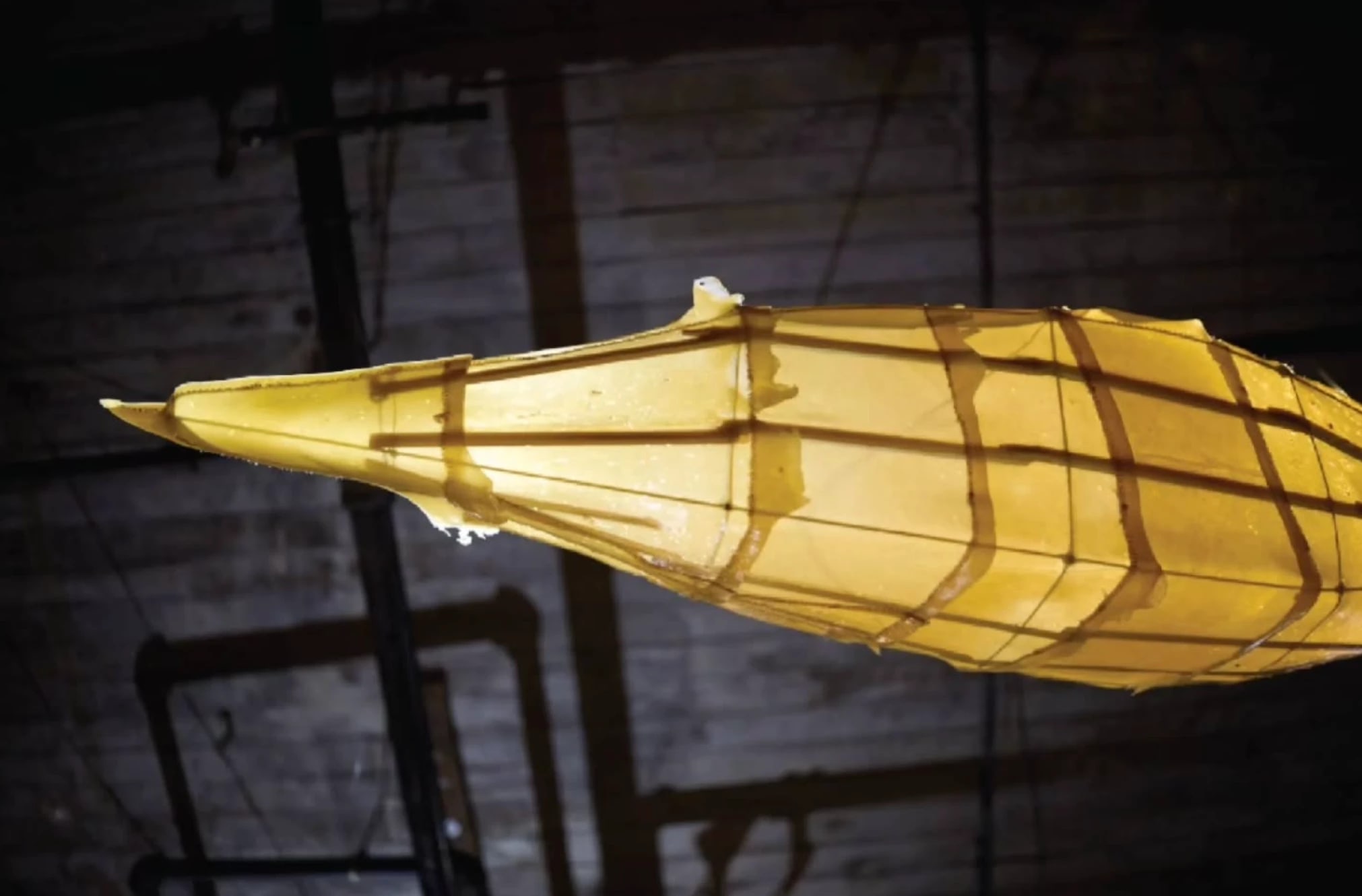 a lantern sculpture glowing yellow against a dark ceiling