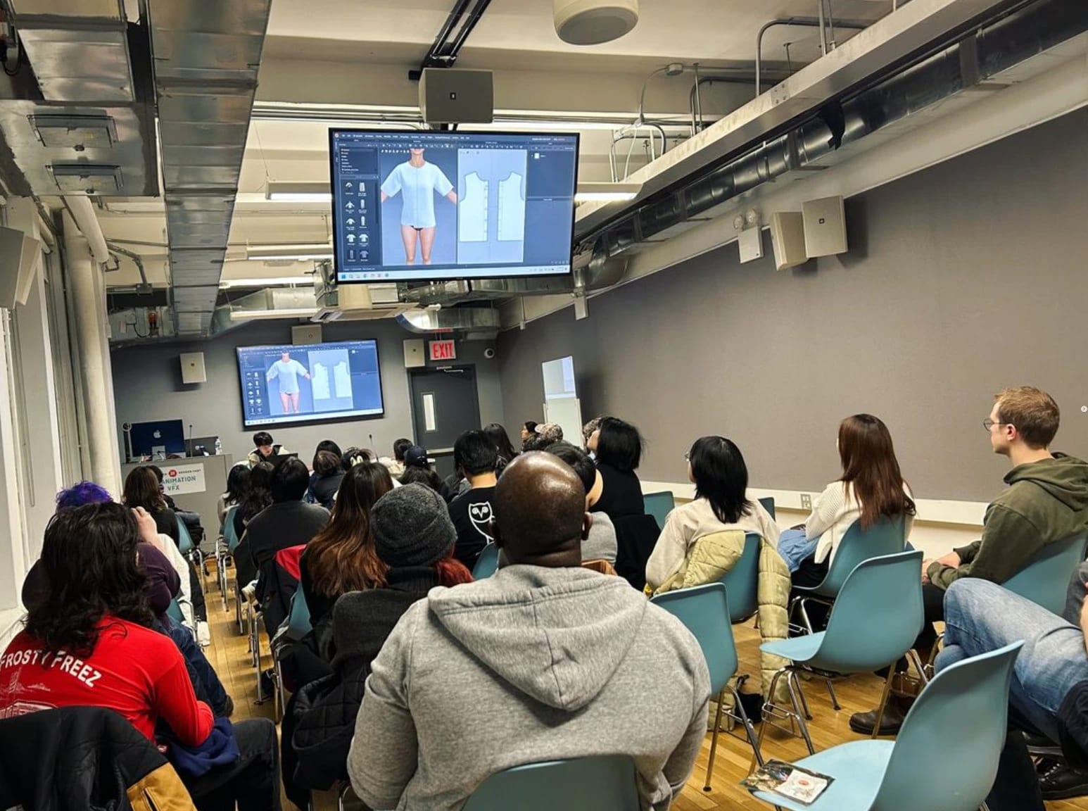 A room of students look ahead to the front at a presenter who is demonstrating 3d modeling software