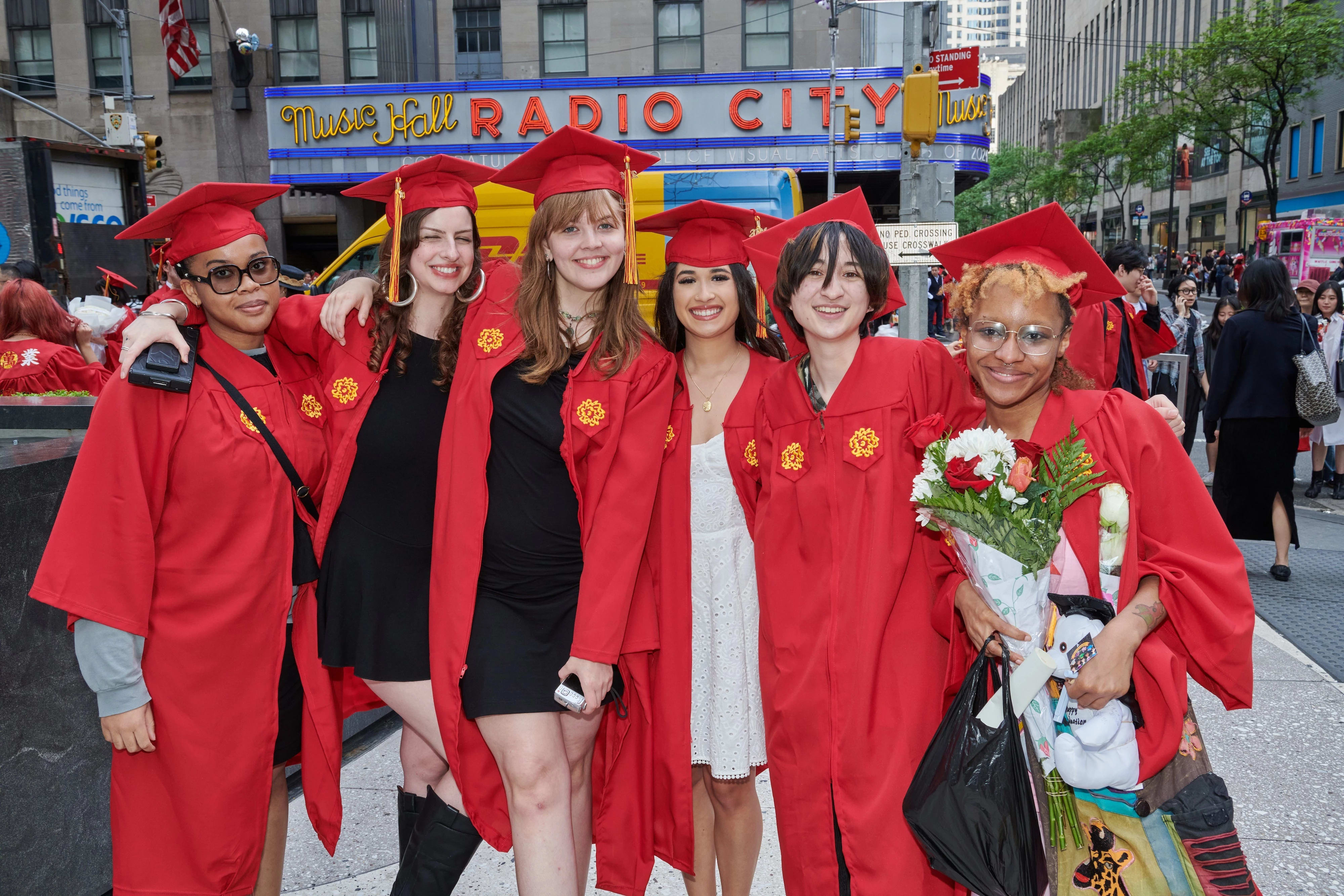 A group of graduating students in red gowns pose for a photo