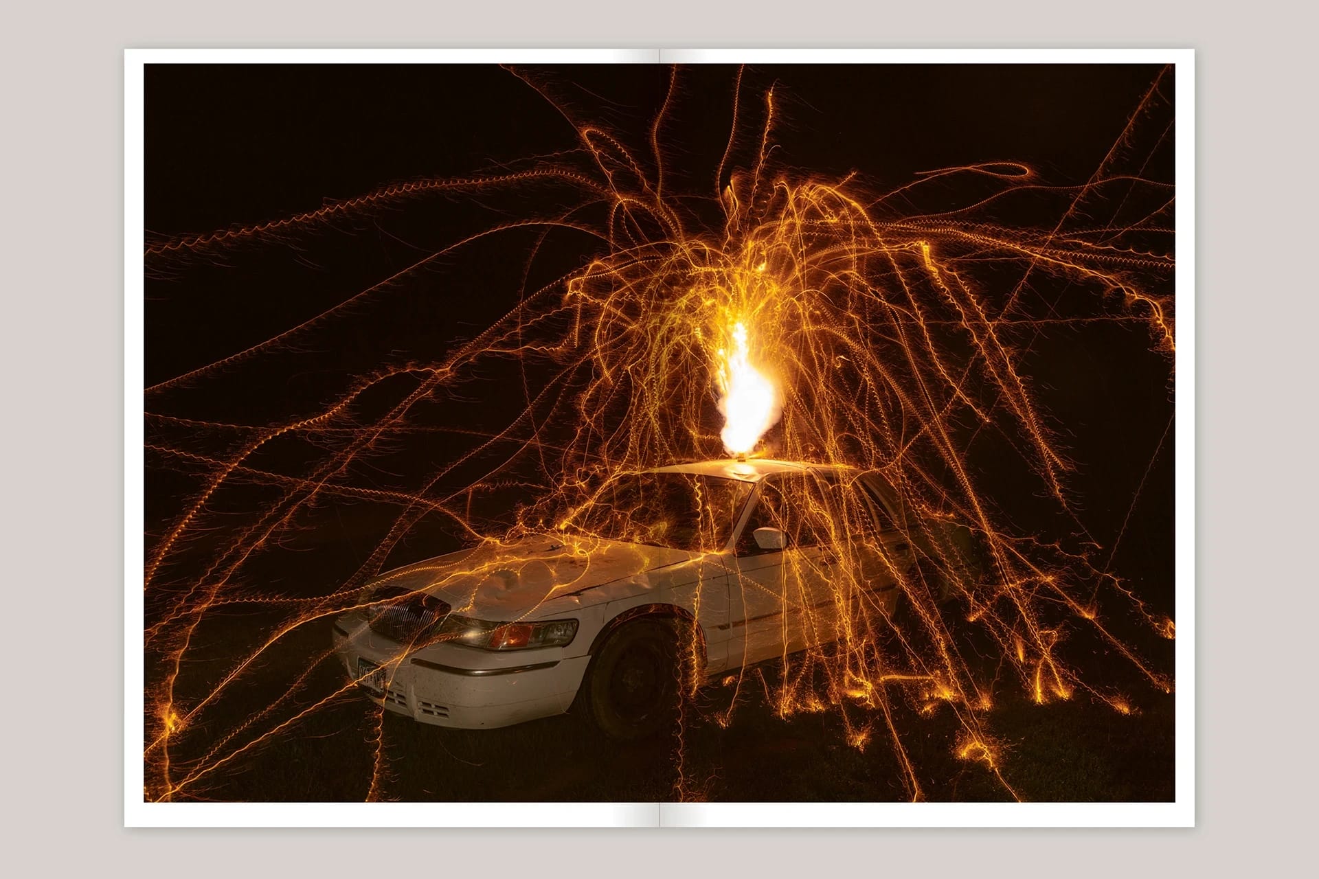 A photo of a white car with a firework sprinkling down around it from its roof