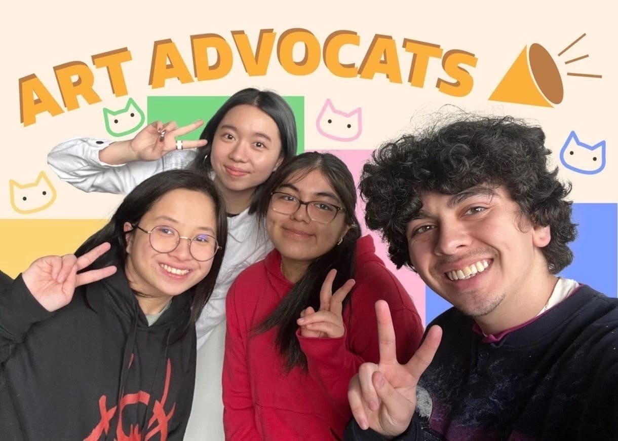 A group of four students hold up peace signs and smile with the word "art advocats" behind them