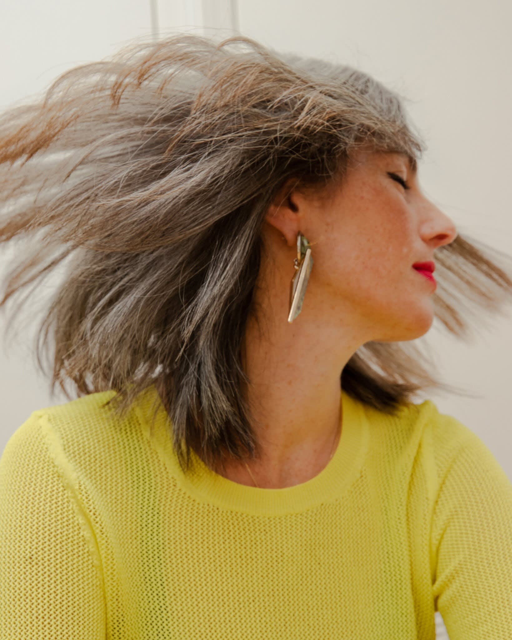 A woman turns her head to her left quickly so that her hair fans out around her.