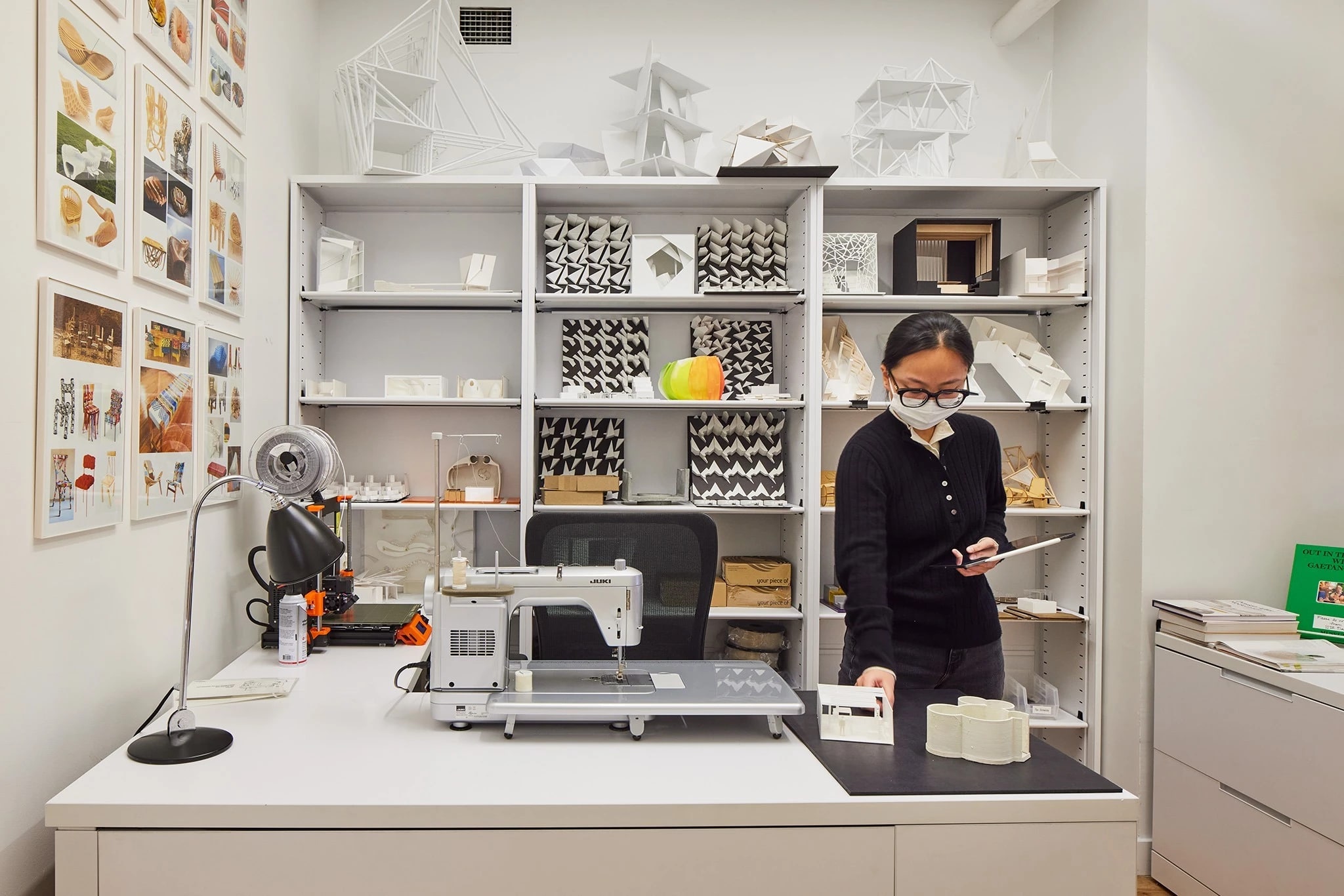 Student arranging their workspace in a maker lab furnished with a sewing machine and textile samples.