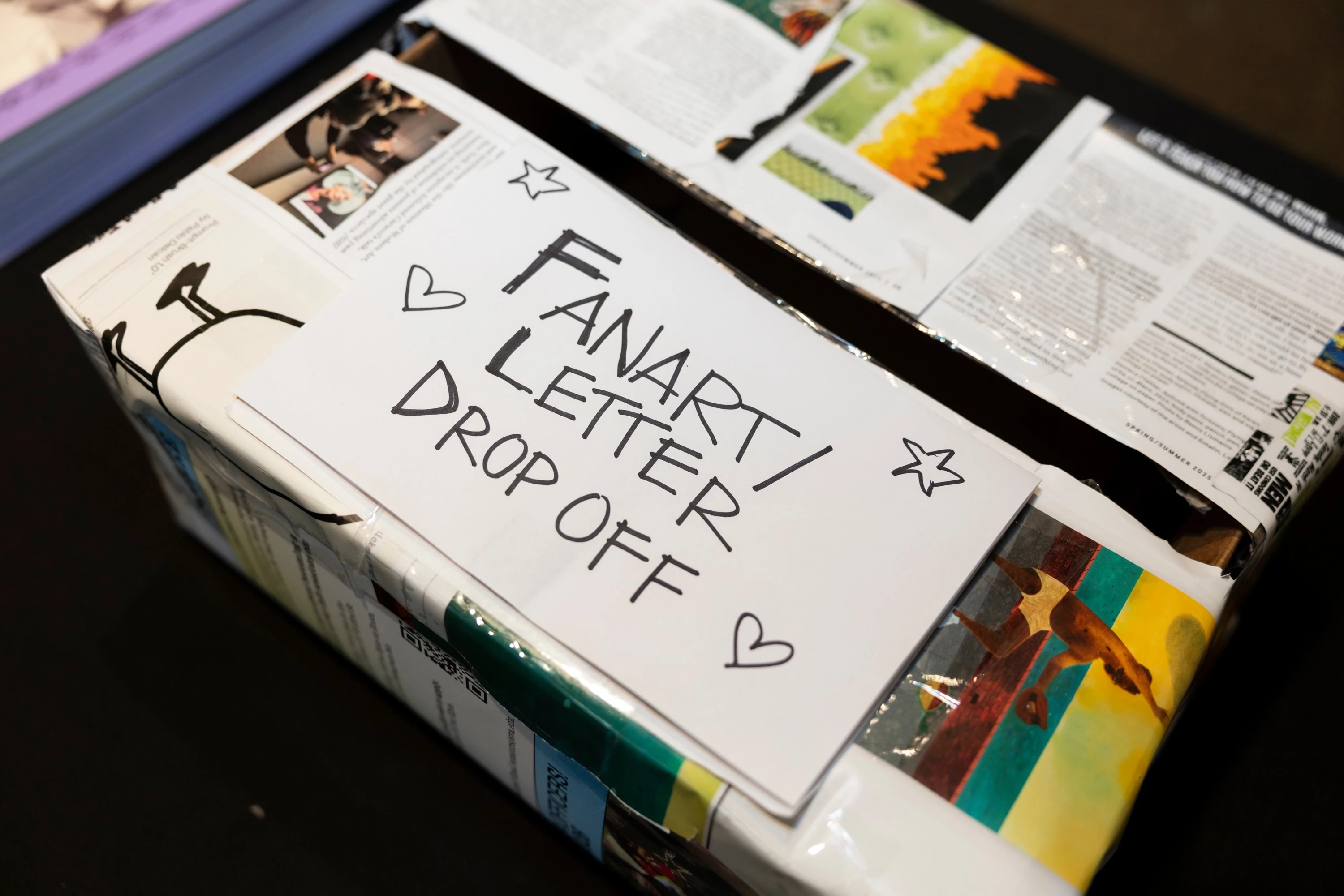 A brightly colored box labeled ‘FAN ART/LETTER DROP OFF,’ with little hearts handrawn around the sign