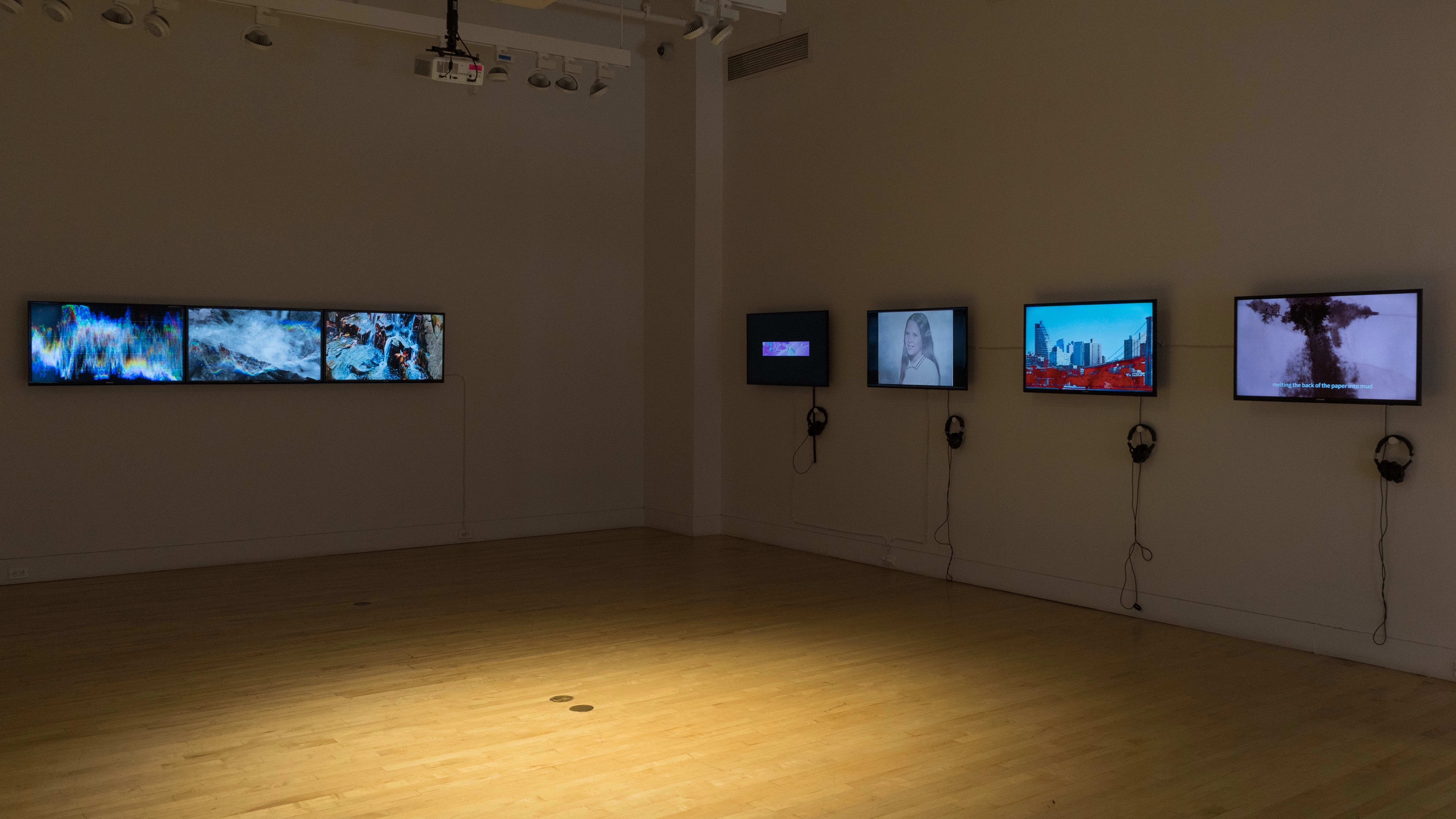 On the left are three screens hung in a horizontal row, end-to-end, playing abstract video work. On the wall to the right are four monitors playing reels of various video work.
