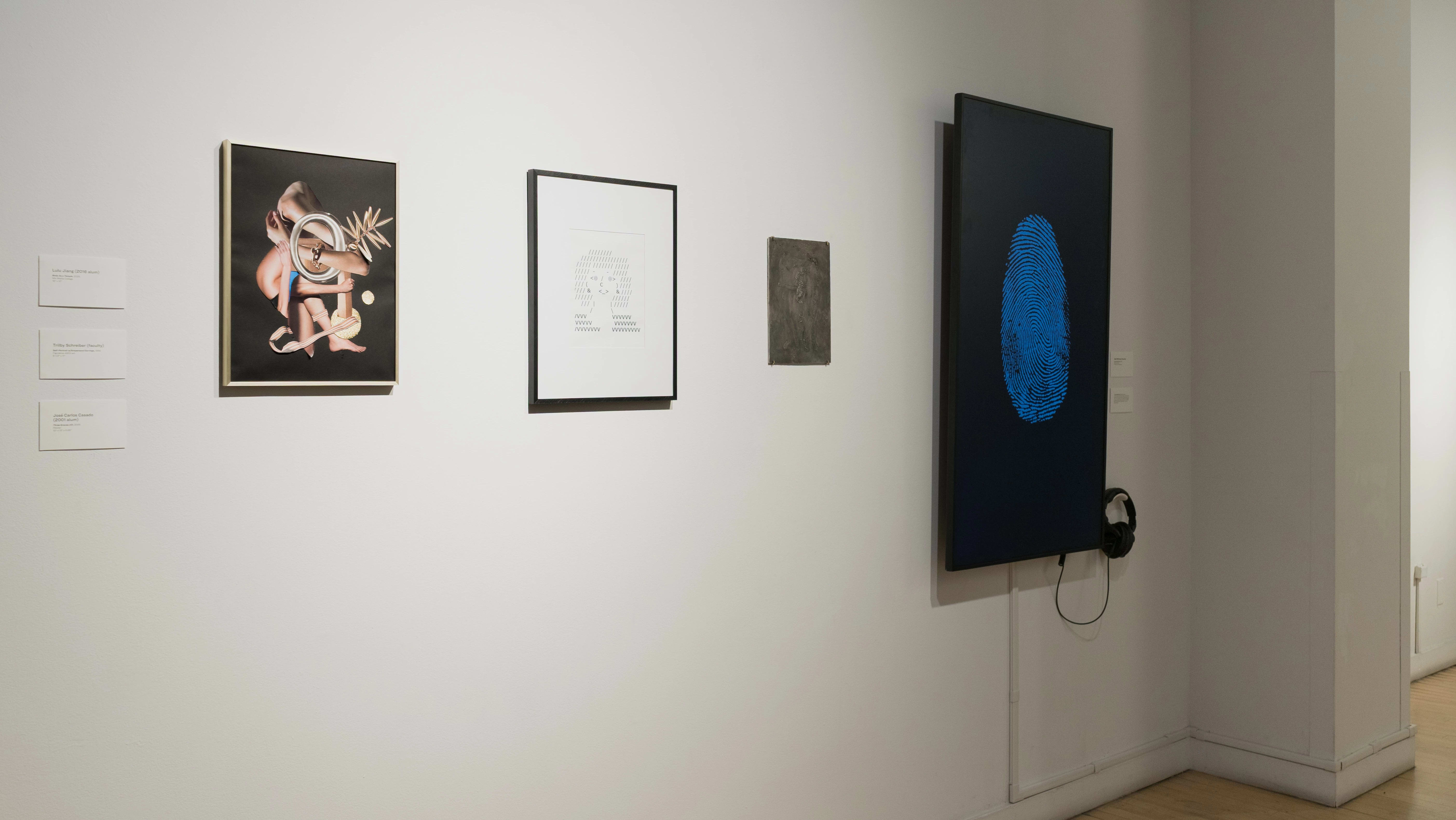 Continuing into the other hallway, two framed works are displayed next to a small, dark, unframed work. To the right of them, a monitor displays a large blue fingerprint.